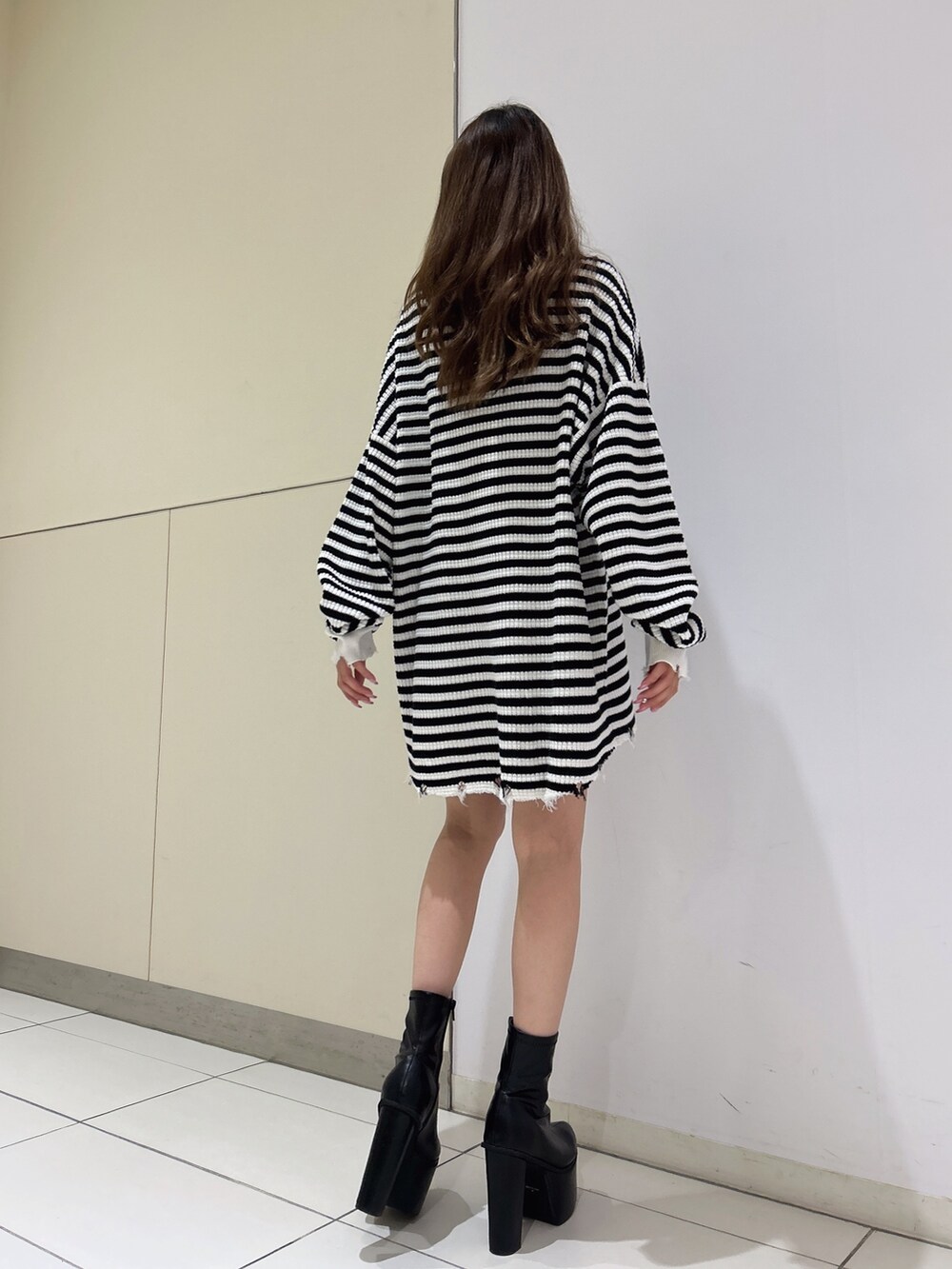 ホワイト系のニット/セーター、ブラック系のブーツを着用したレディースの秋コーディネートの2枚目の写真