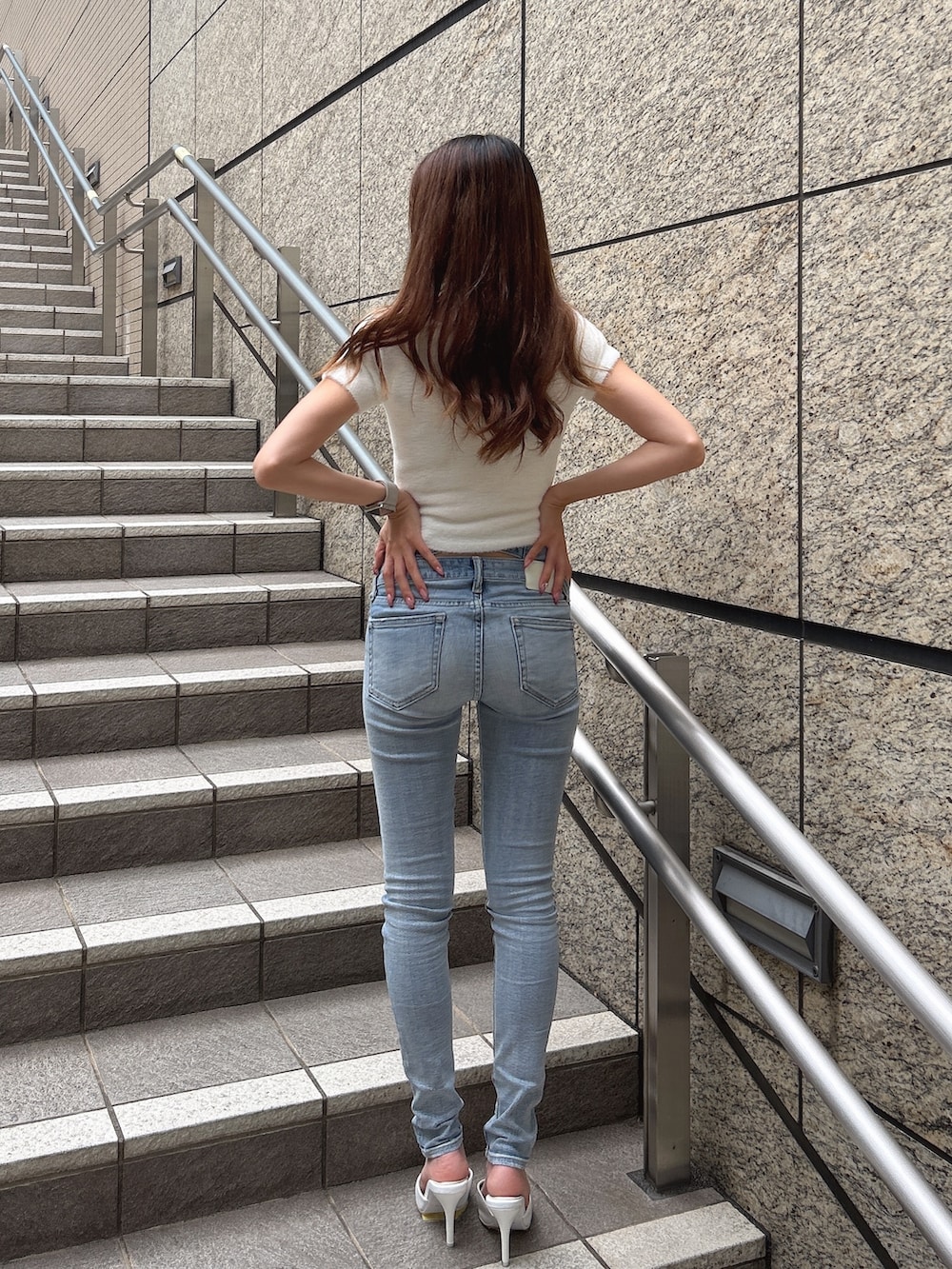 ブルー系のデニムパンツ、ホワイト系のニット/セーター、ホワイト系のパンプスを着用したレディースの秋コーディネートの2枚目の写真