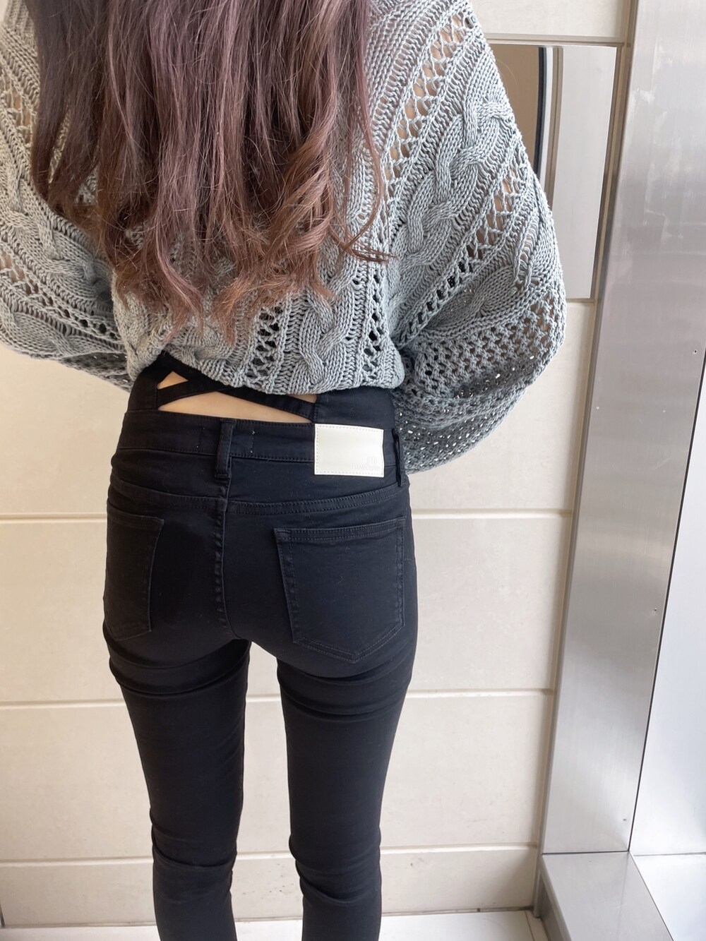 オレンジ系のニット/セーター、ブラック系のデニムパンツ、ホワイト系のパンプスを着用したレディースの冬コーディネートの6枚目の写真