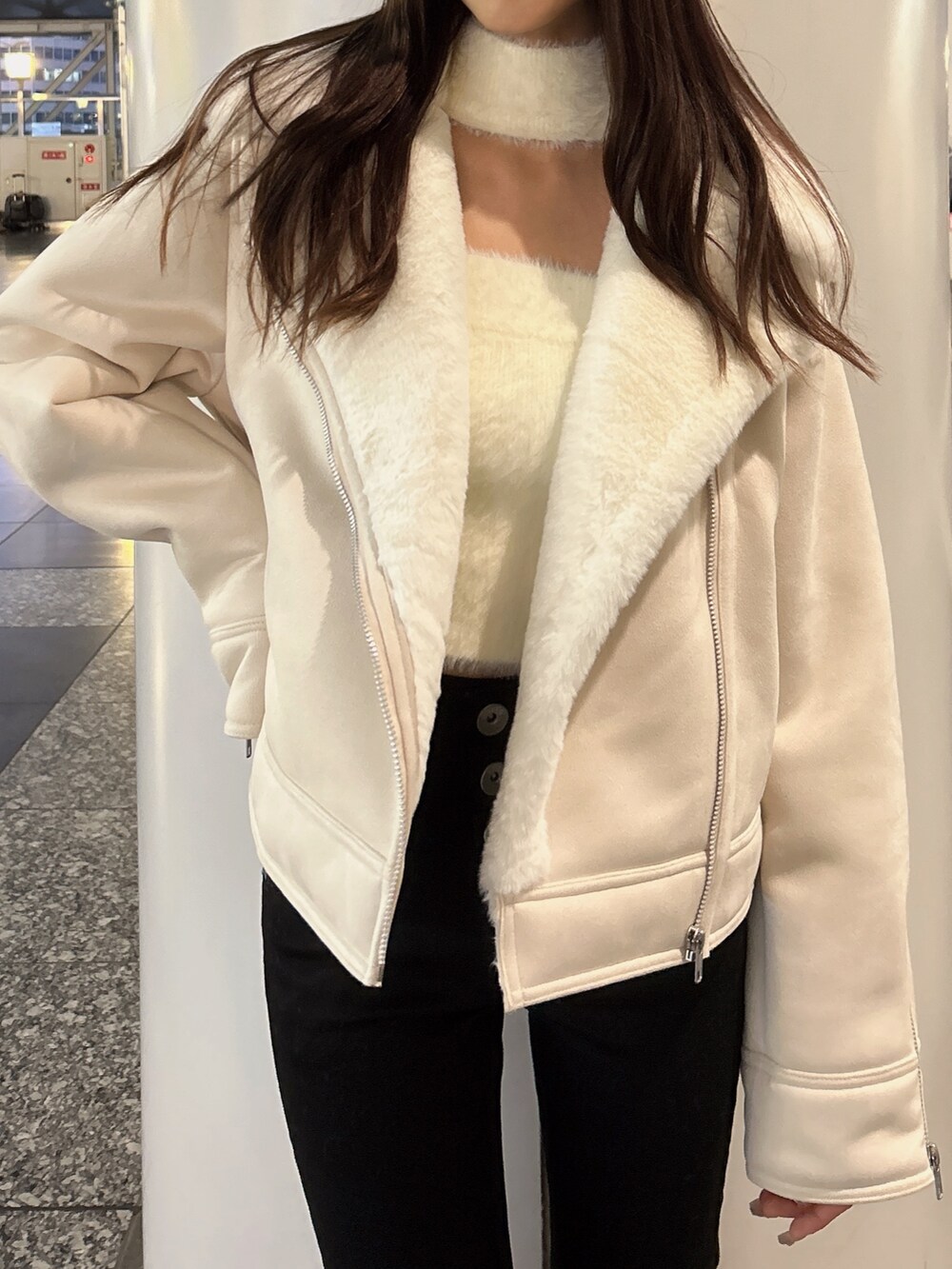 ホワイト系のムートンコート、ホワイト系のニット/セーター、ブラック系のデニムパンツを着用したレディースの秋コーディネートの3枚目の写真