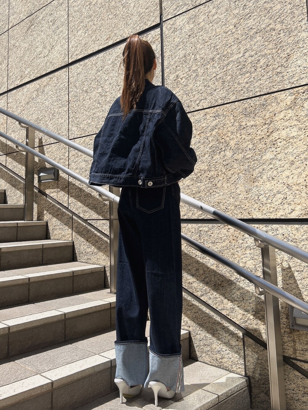 ブルー系のデニムジャケット、ブラック系のデニムパンツ、ブラック系のパンプスを着用したレディースの秋コーディネートの2枚目の写真