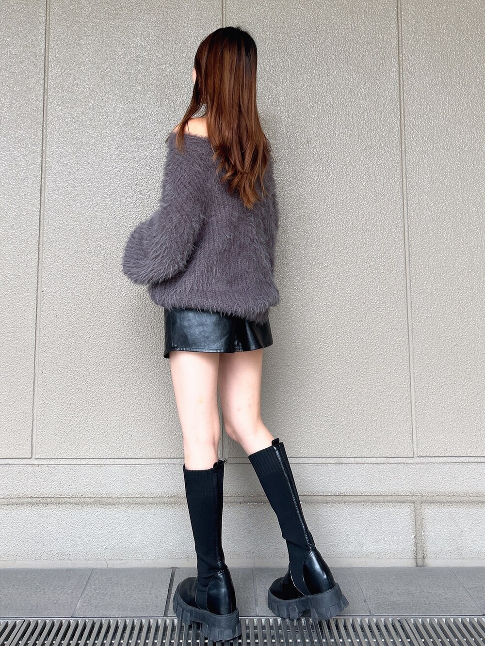 グレー系のニット/セーター、ブラック系のスカート、ブラック系のブーツを着用したレディースの秋コーディネートの3枚目の写真