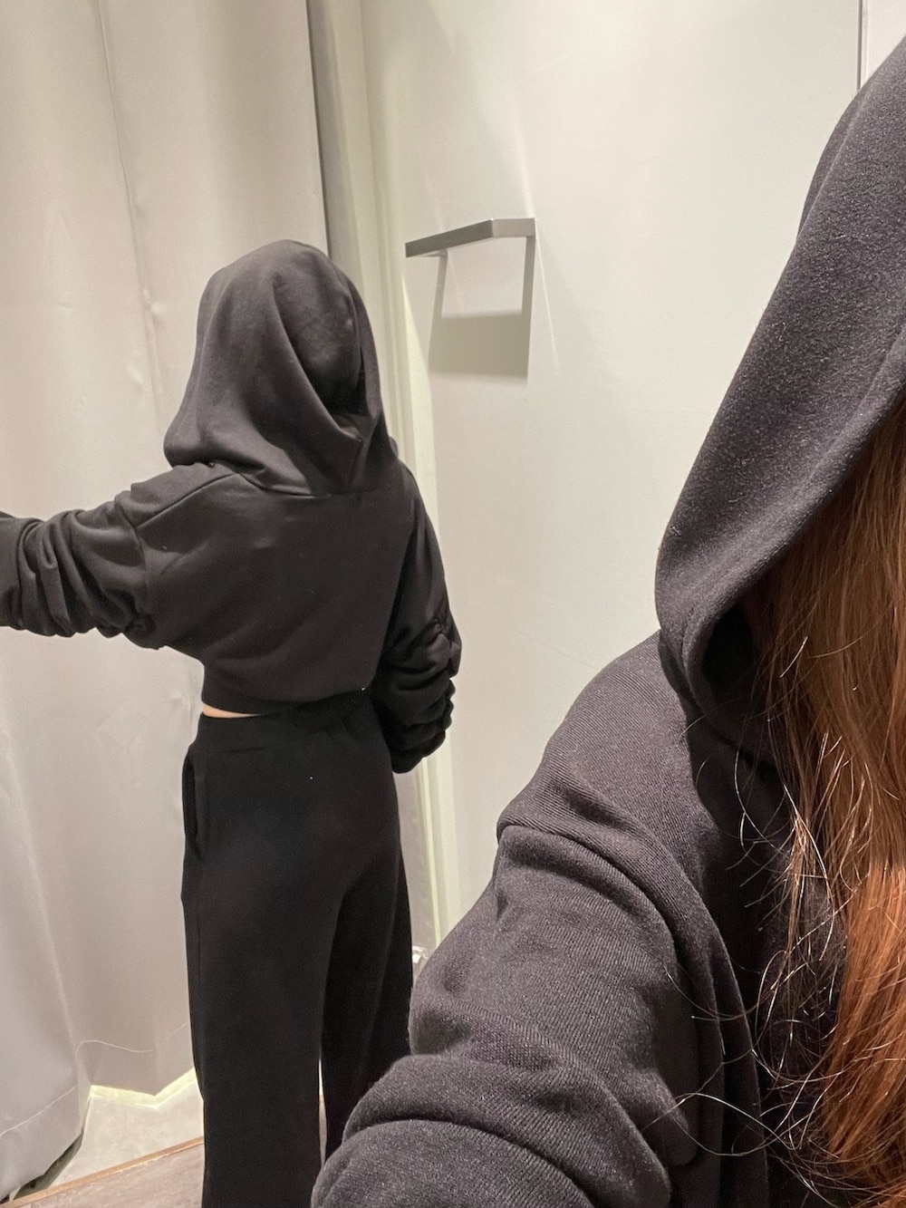ホワイト系のスニーカー、ブラック系のスウェットパンツ、ブラック系のパーカーを着用したレディースの冬コーディネートの5枚目の写真