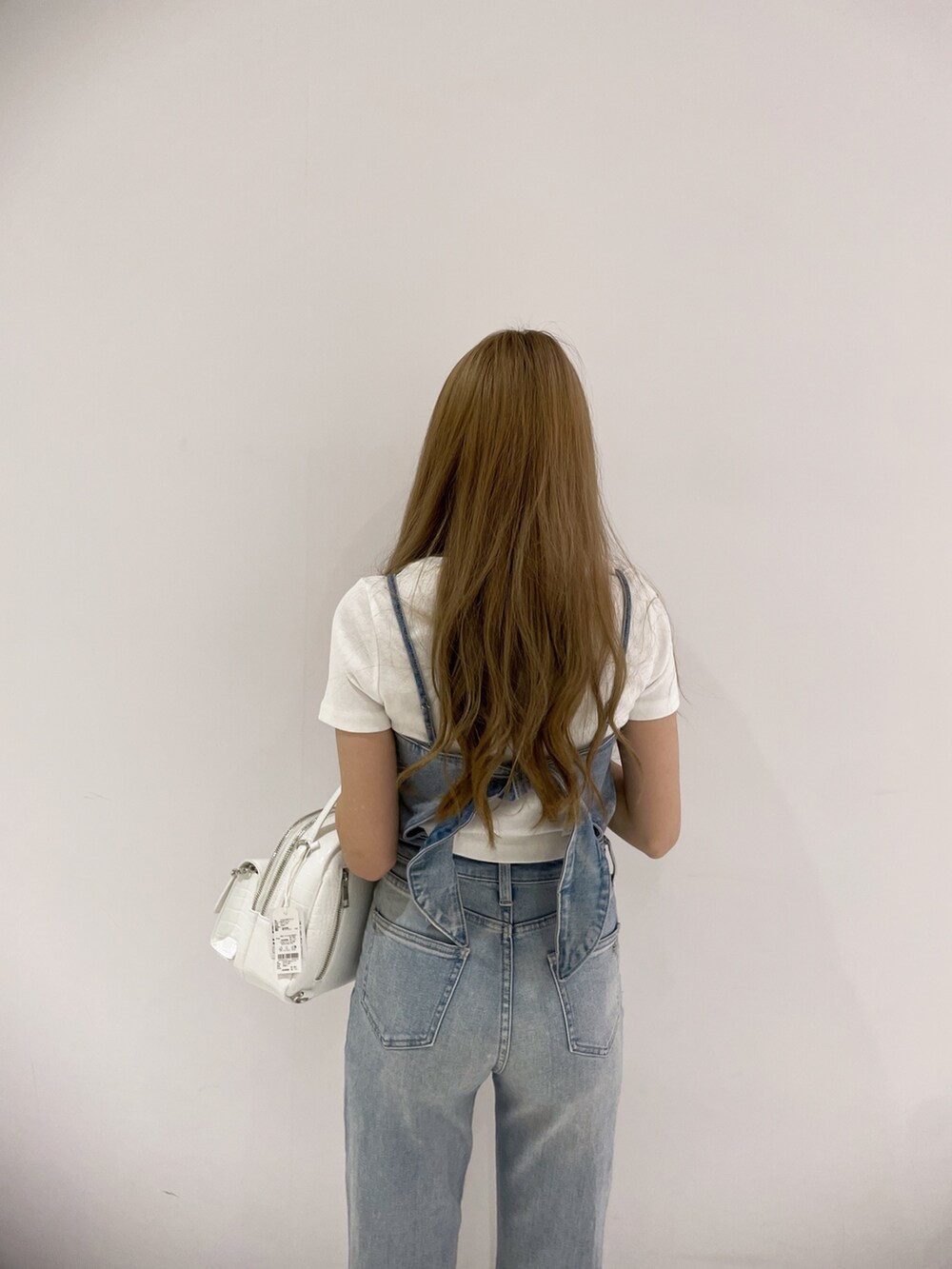 ブルー系のサロペット/オーバーオール、ホワイト系のTシャツ/カットソー、ブラック系のバックパック/リュックを着用したレディースの春コーディネートの5枚目の写真