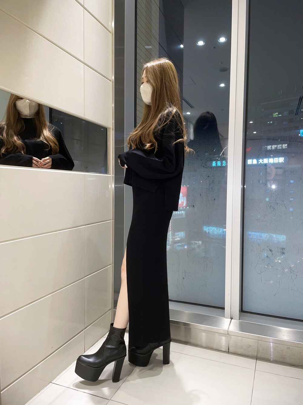 ブラック系のスカート、ブラック系のニット/セーター、ブラック系のブーツを着用したレディースの冬コーディネートの2枚目の写真