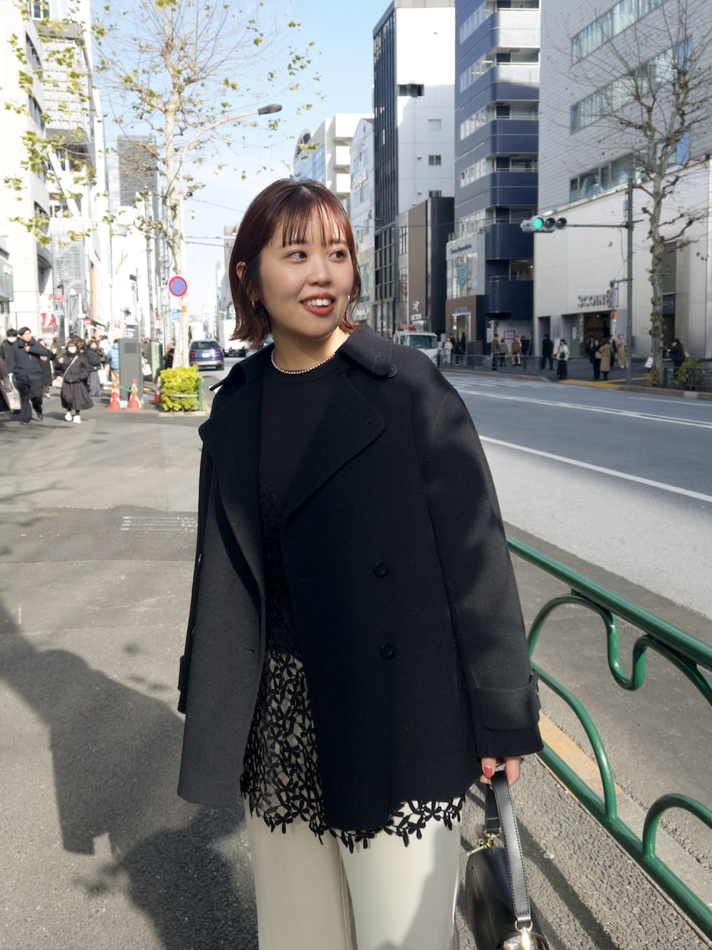 ブラック系のピーコート、ブラック系のキャミソール、ベージュ系のその他パンツを着用したレディースの冬コーディネートの3枚目の写真