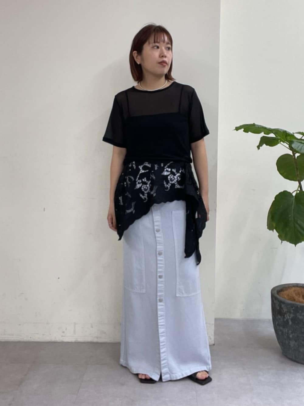 ブルー系のスカート、ブラック系のTシャツ/カットソー、ブラック系のサンダルを着用したレディースの春コーディネートの7枚目の写真