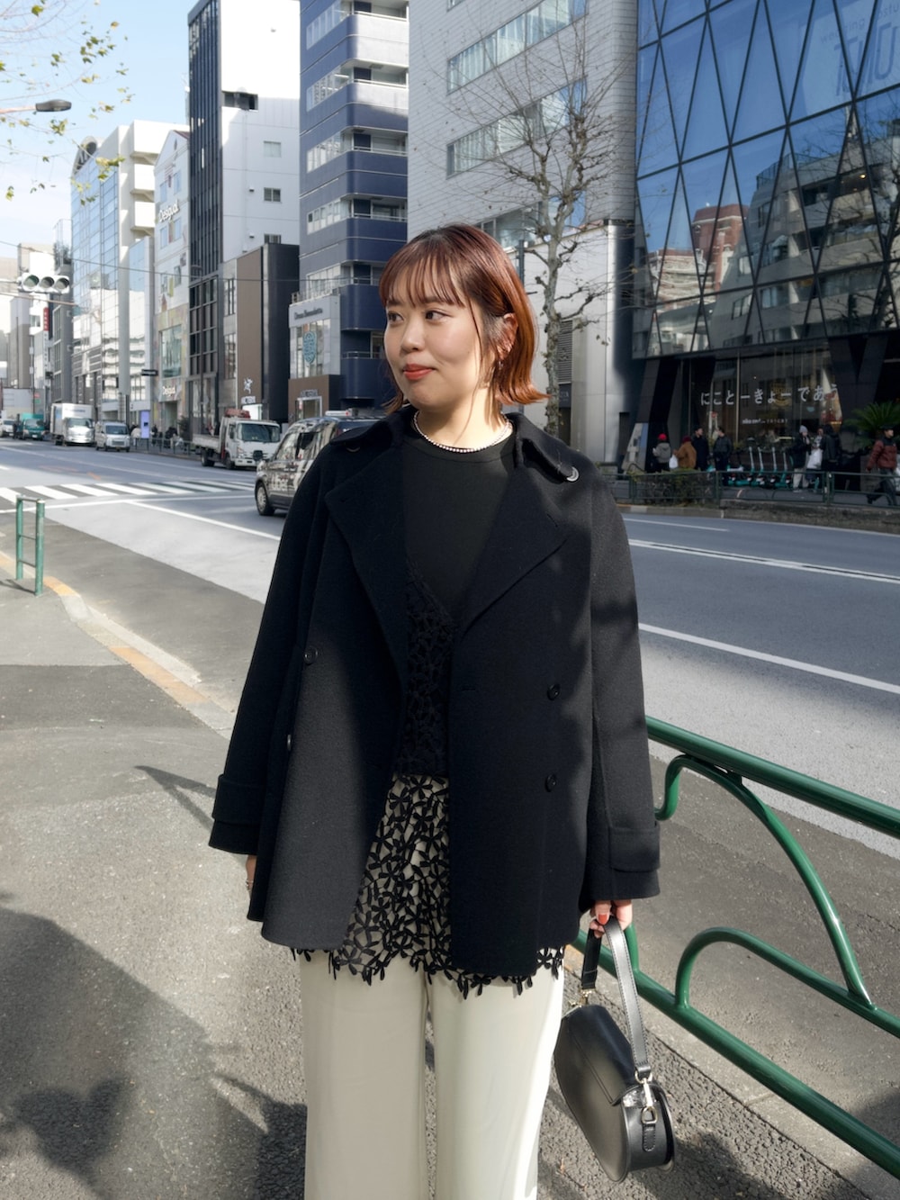 ブラック系のピーコート、ブラック系のキャミソール、ベージュ系のその他パンツを着用したレディースの冬コーディネートの4枚目の写真