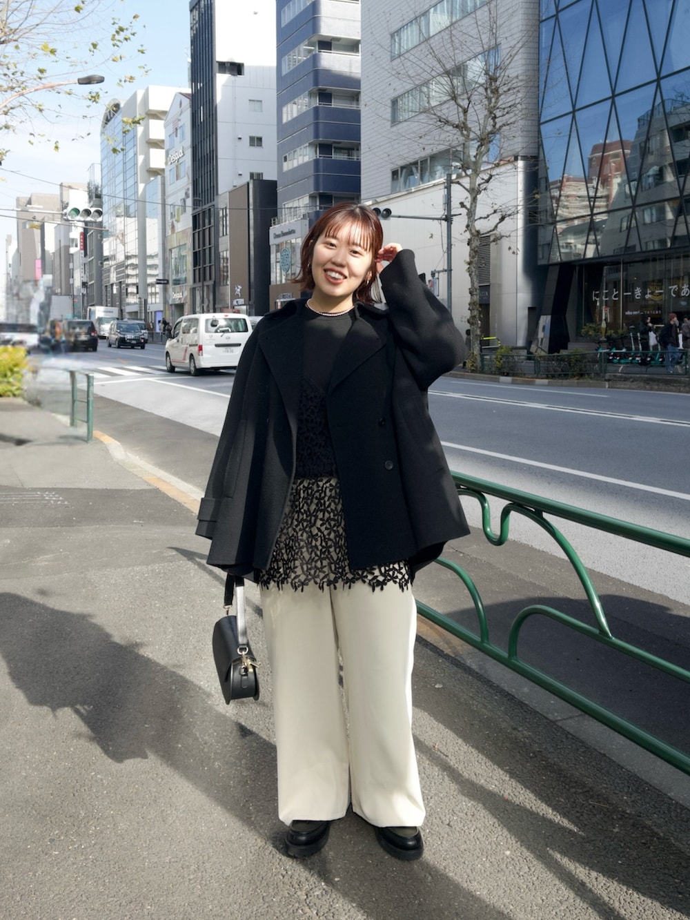 ブラック系のピーコート、ブラック系のキャミソール、ベージュ系のその他パンツを着用したレディースの冬コーディネートの2枚目の写真