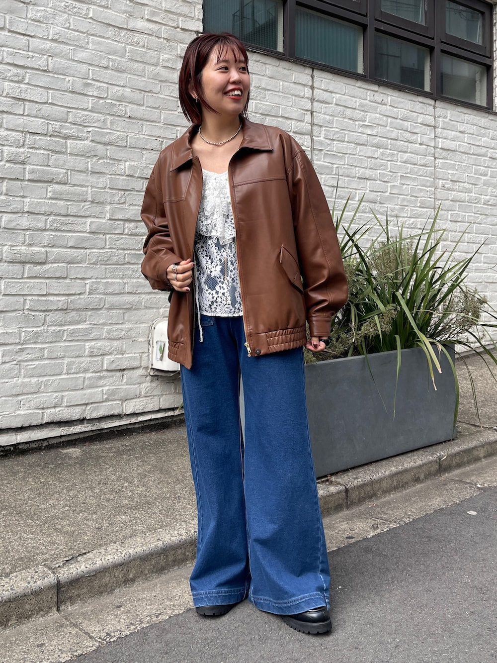 ブラウン系のブルゾン、ホワイト系のシャツ/ブラウス、ブルー系のデニムパンツを着用したレディースの冬コーディネートの2枚目の写真