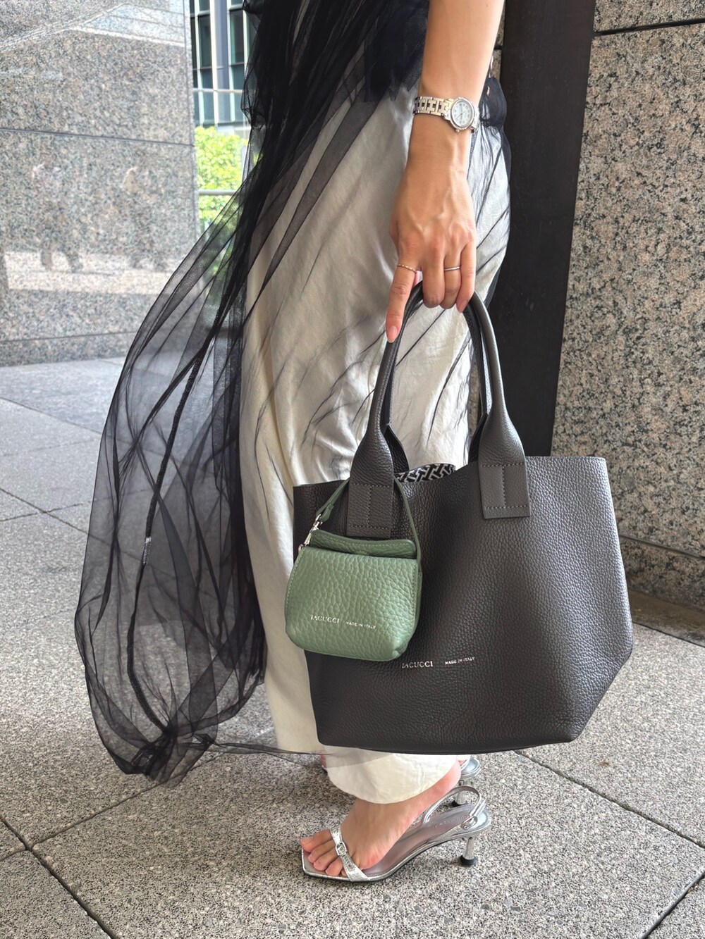 グレー系のトートバッグ、グリーン系のその他小物を着用したレディースの夏コーディネートの2枚目の写真