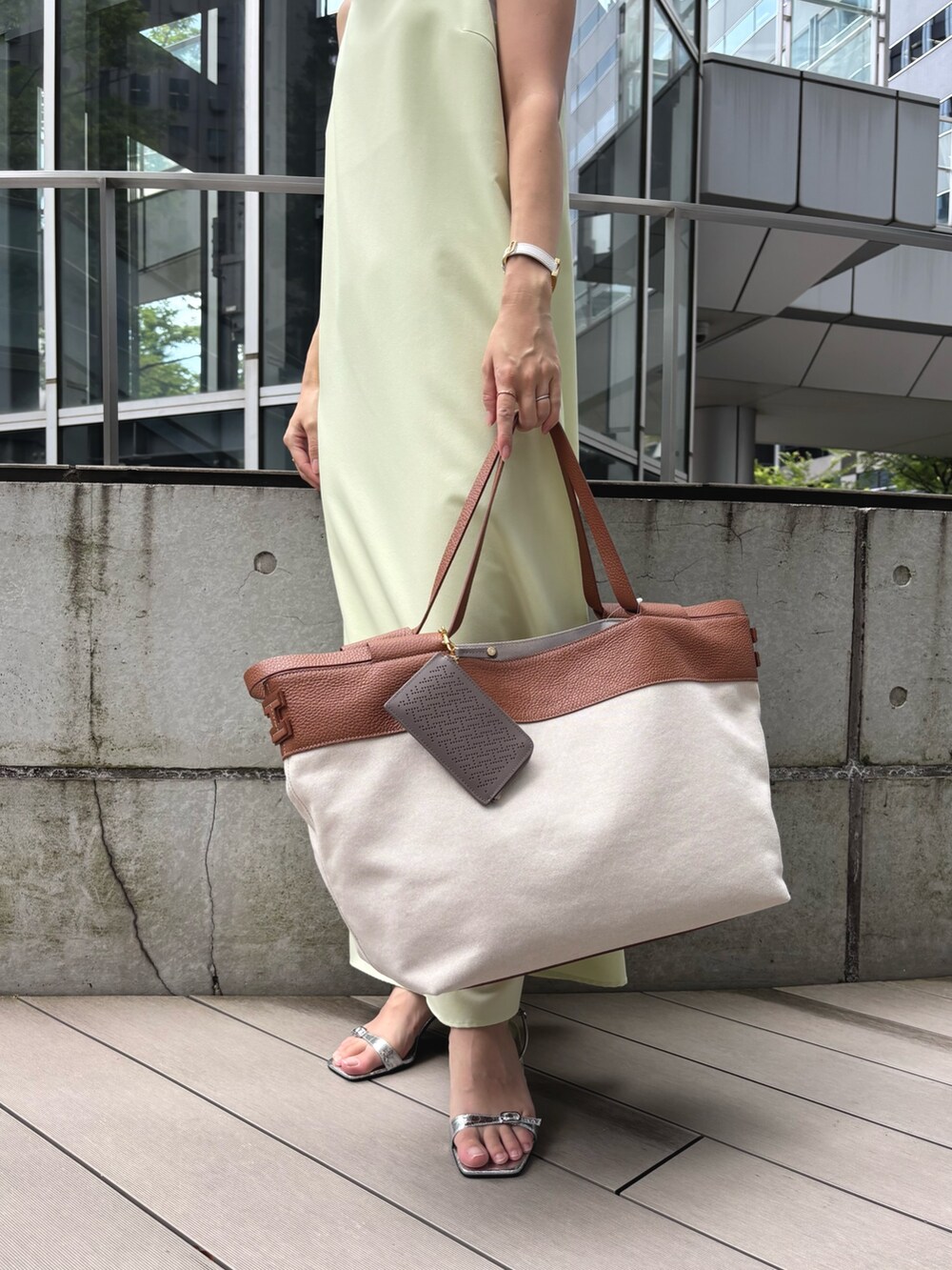 イエロー系のトートバッグ、ベージュ系の財布を着用したレディースの夏コーディネートの2枚目の写真