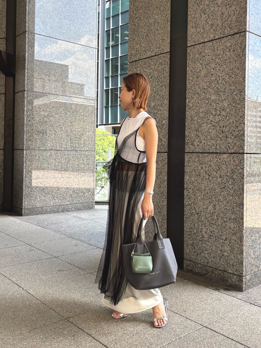 グレー系のトートバッグ、グリーン系のその他小物を着用したレディースの夏コーディネートの3枚目の写真