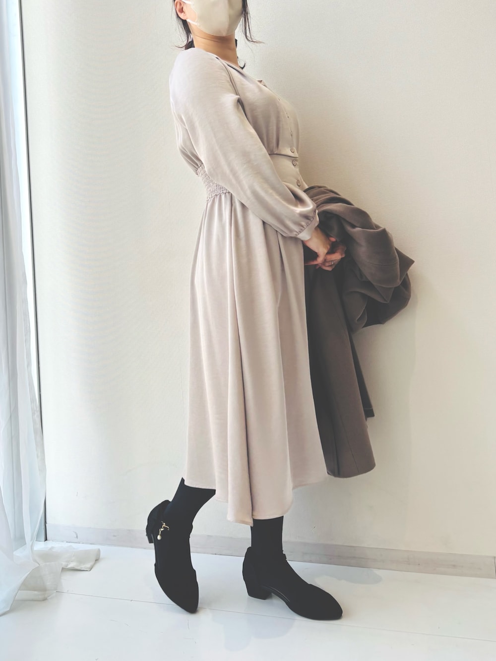 ベージュ系のワンピース、ベージュ系のノーカラーコートを着用したレディースの冬コーディネートの2枚目の写真