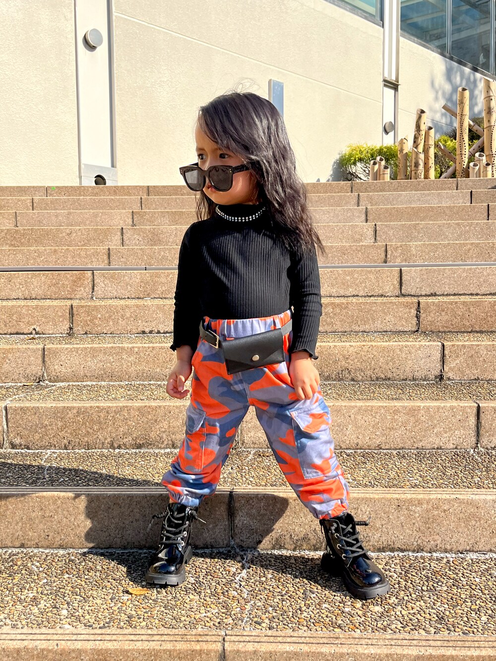 ブラック系のニット/セーター、オレンジ系のカーゴパンツを着用したキッズの冬コーディネートの2枚目の写真