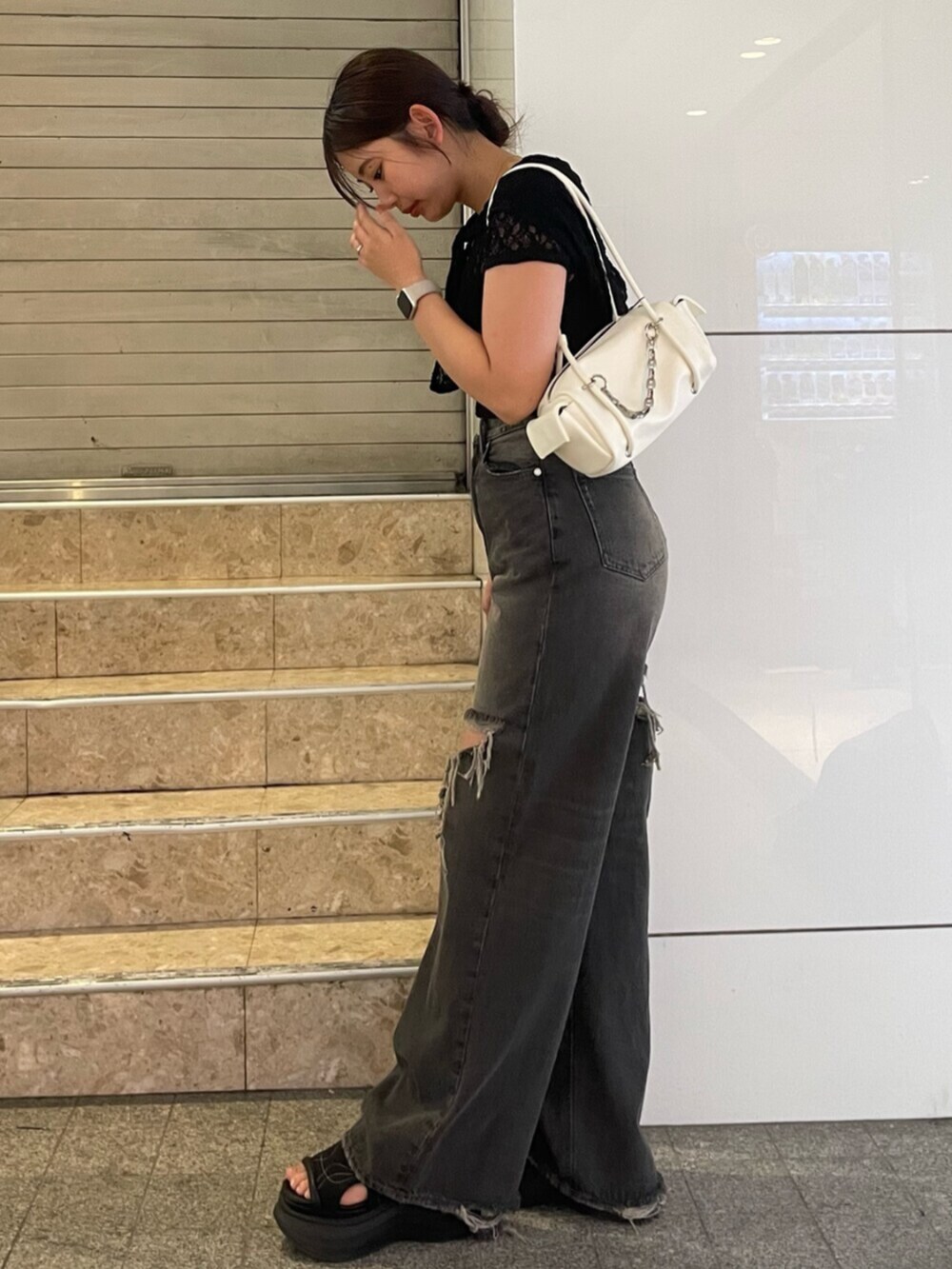 ブラック系のサンダル、ホワイト系のハンドバッグ、ブラック系のTシャツ/カットソーを着用したレディースの夏コーディネートの3枚目の写真