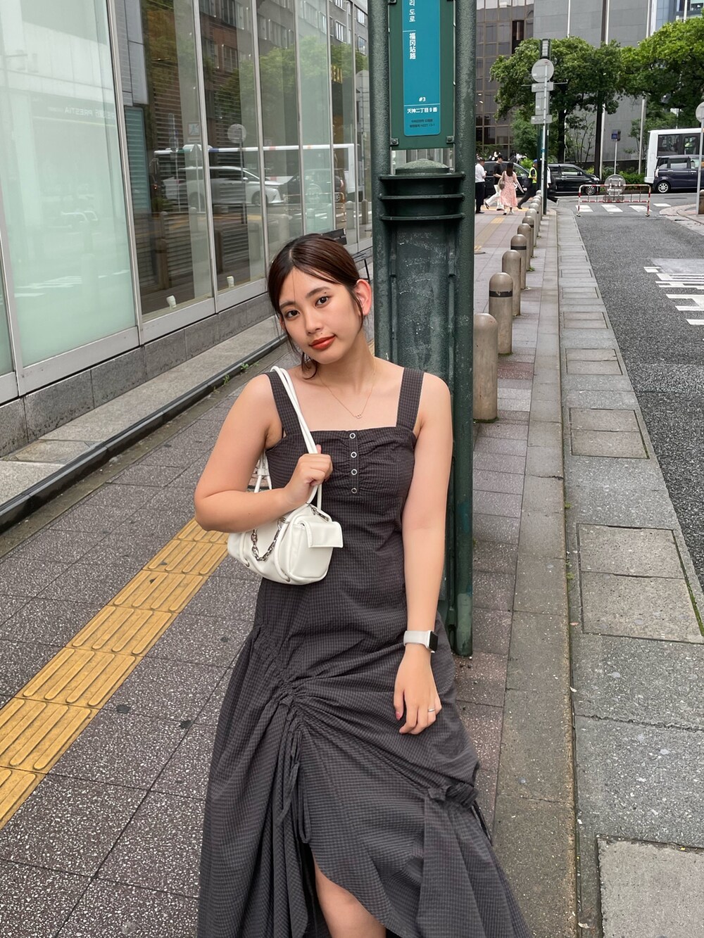グレー系のワンピース、ブラック系のサンダル、ホワイト系のハンドバッグを着用したレディースの夏コーディネートの4枚目の写真