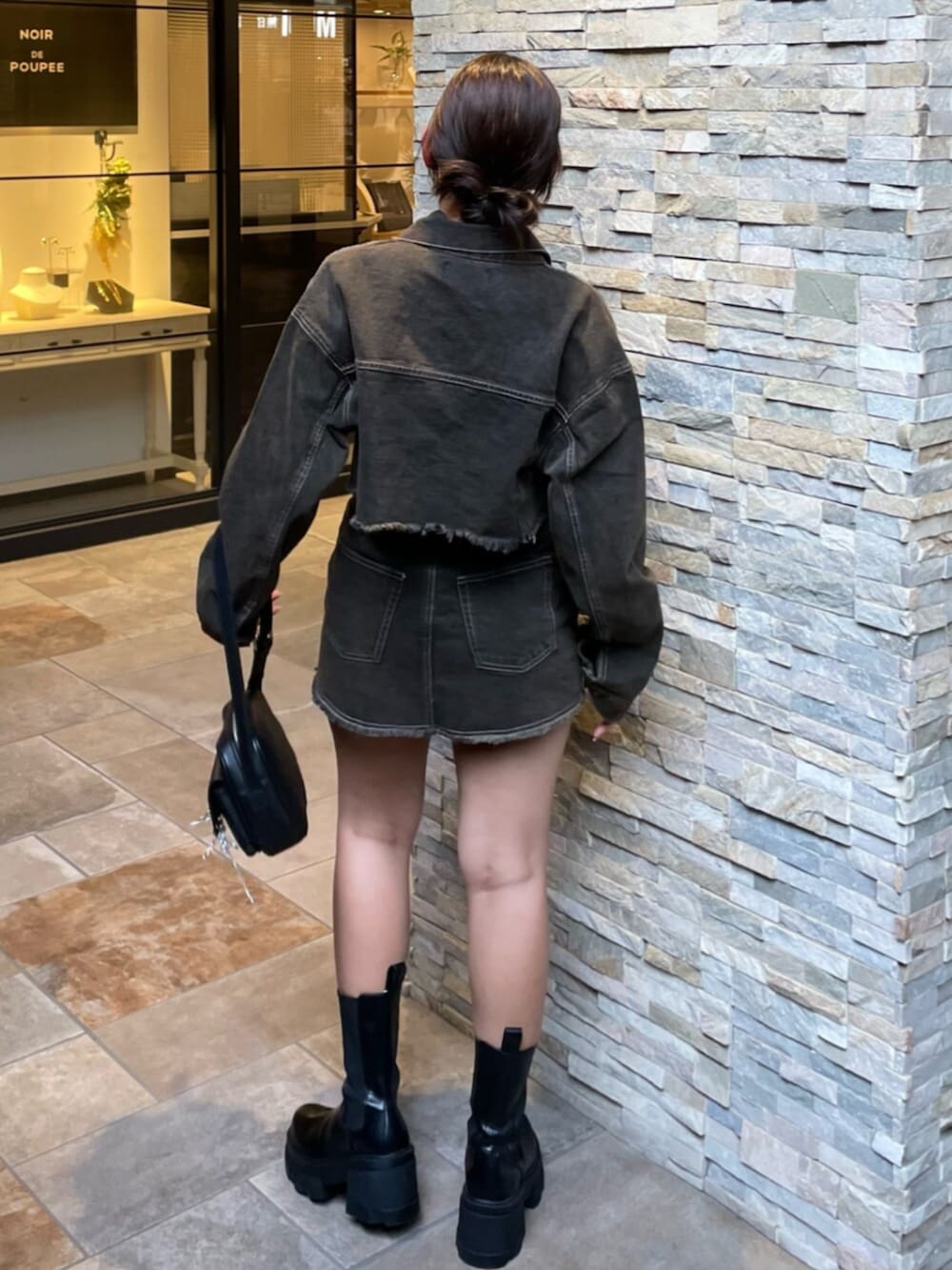 ブラック系のブーツ、ブラック系のハンドバッグ、ブラウン系のデニムジャケットを着用したレディースの秋コーディネートの3枚目の写真