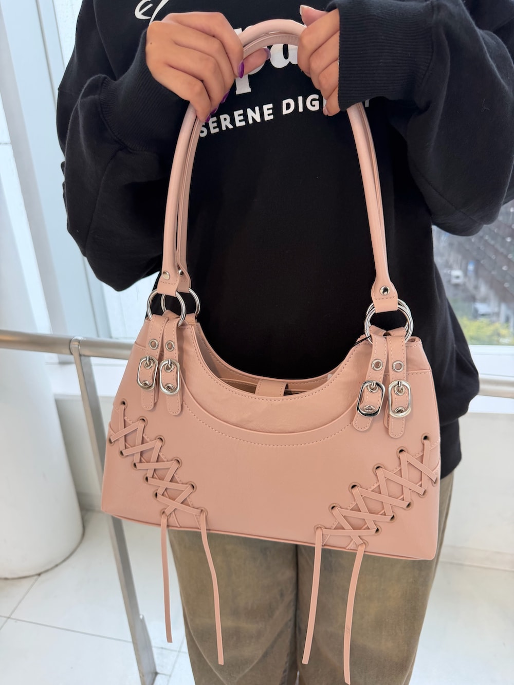 ブラック系のスウェット、ピンク系のショルダーバッグ、ブラウン系のデニムパンツを着用したレディースの秋コーディネートの6枚目の写真