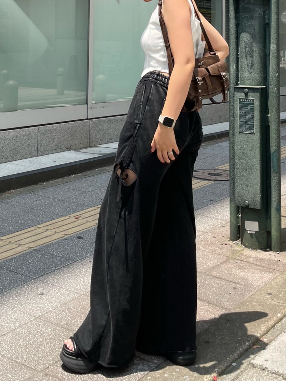 ブラック系のサンダル、ブラウン系のハンドバッグ、ホワイト系のニット/セーターを着用したレディースの夏コーディネートの2枚目の写真