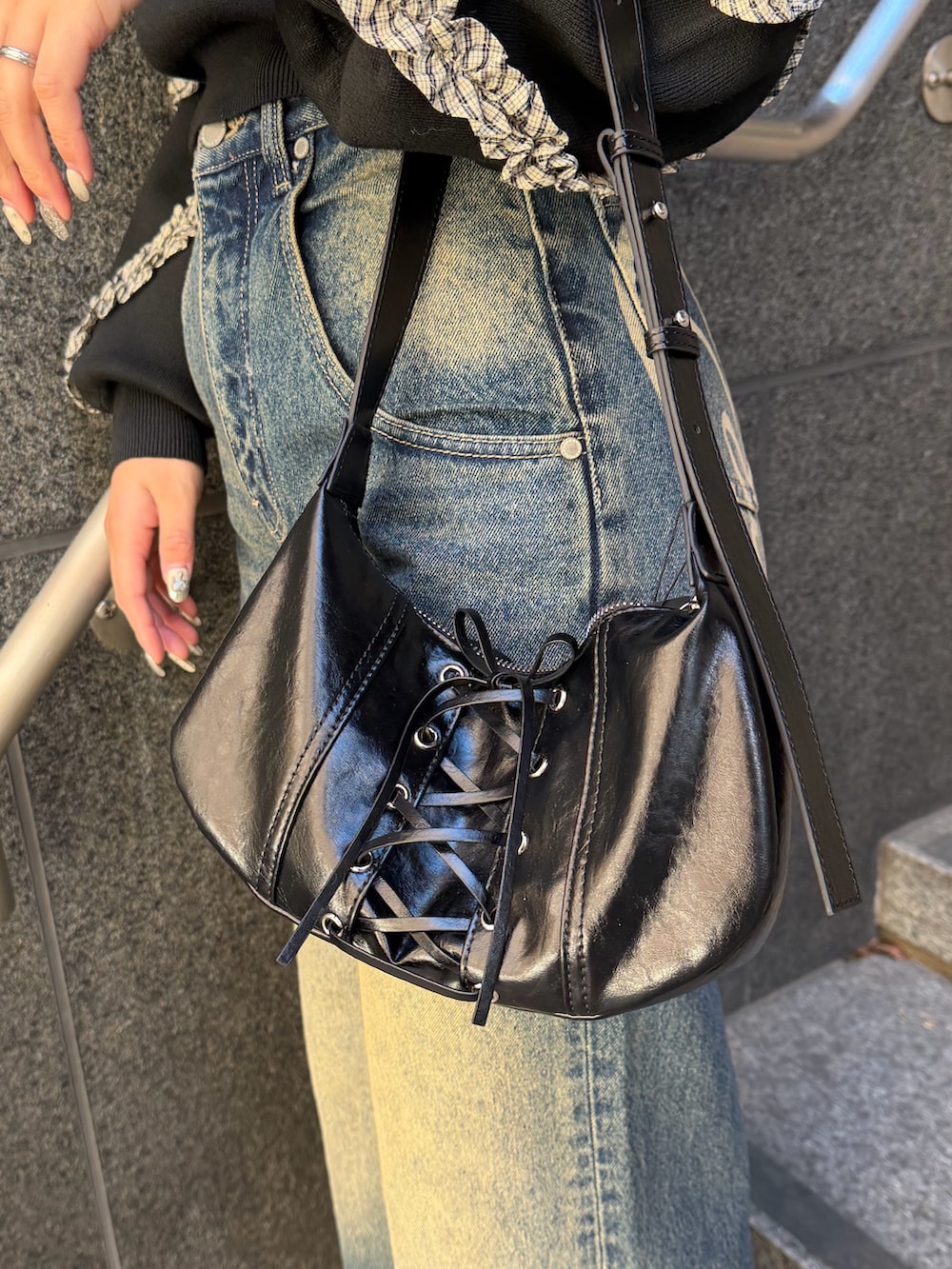 ブラック系のニット/セーター、ブルー系のデニムパンツ、ブラック系のショルダーバッグを着用したレディースの冬コーディネートの7枚目の写真