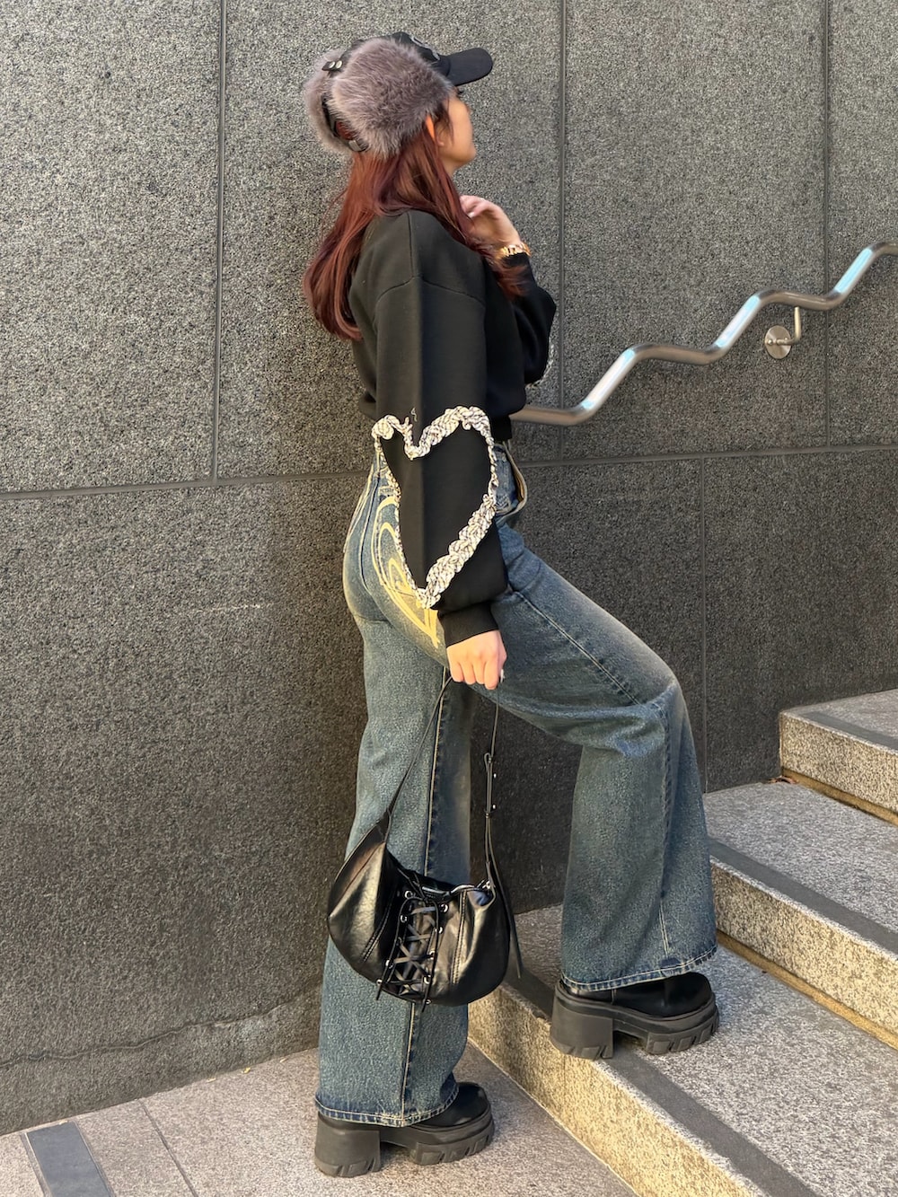 ブラック系のニット/セーター、ブルー系のデニムパンツ、ブラック系のショルダーバッグを着用したレディースの冬コーディネートの2枚目の写真