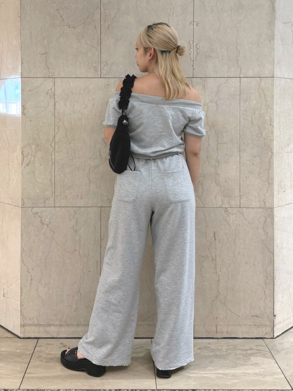 グレー系のスウェット、グレー系のスウェットパンツ、ブラック系のショルダーバッグを着用したレディースの夏コーディネートの3枚目の写真