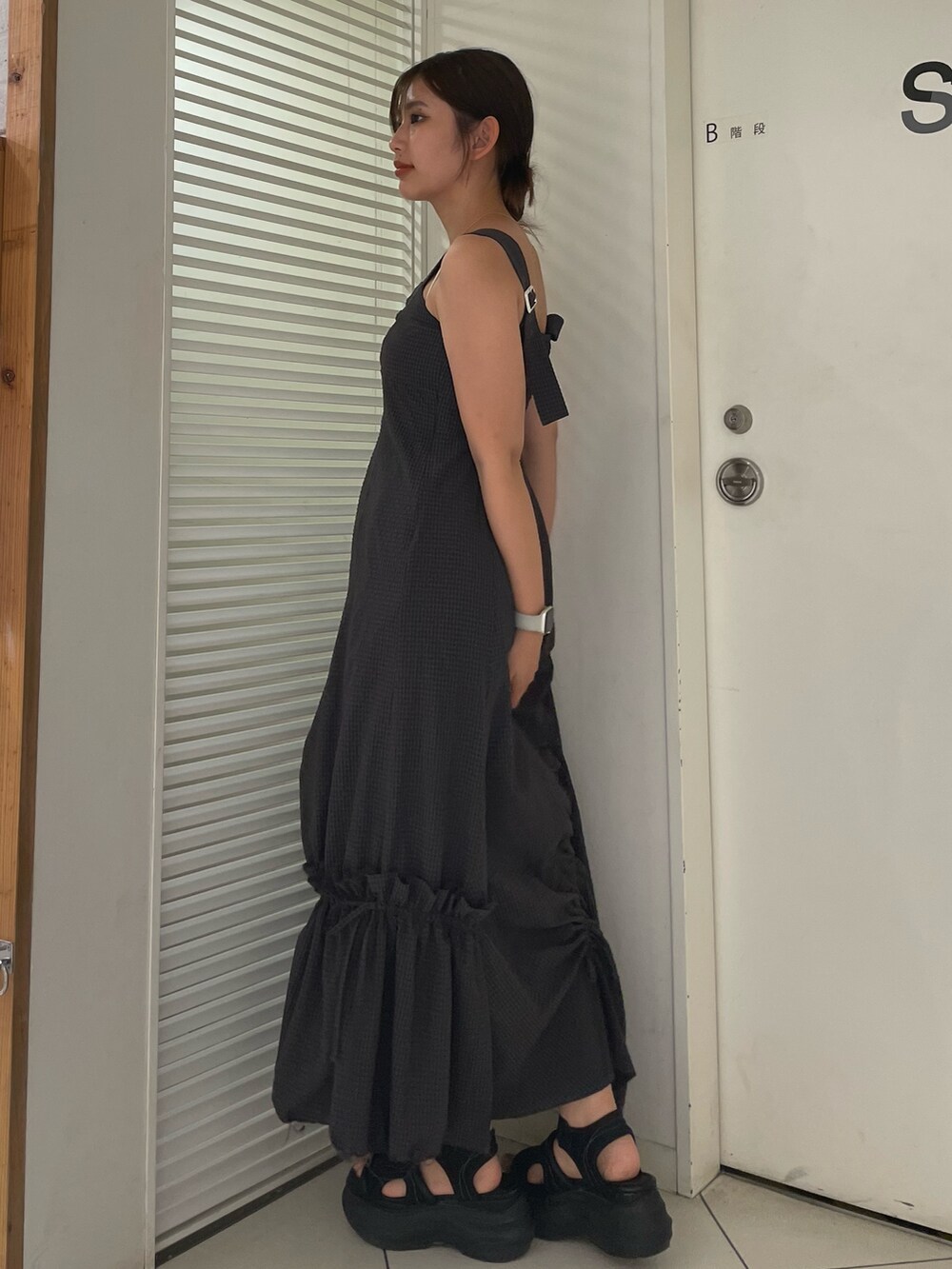 グレー系のワンピース、ブラック系のサンダル、ホワイト系のハンドバッグを着用したレディースの夏コーディネートの2枚目の写真