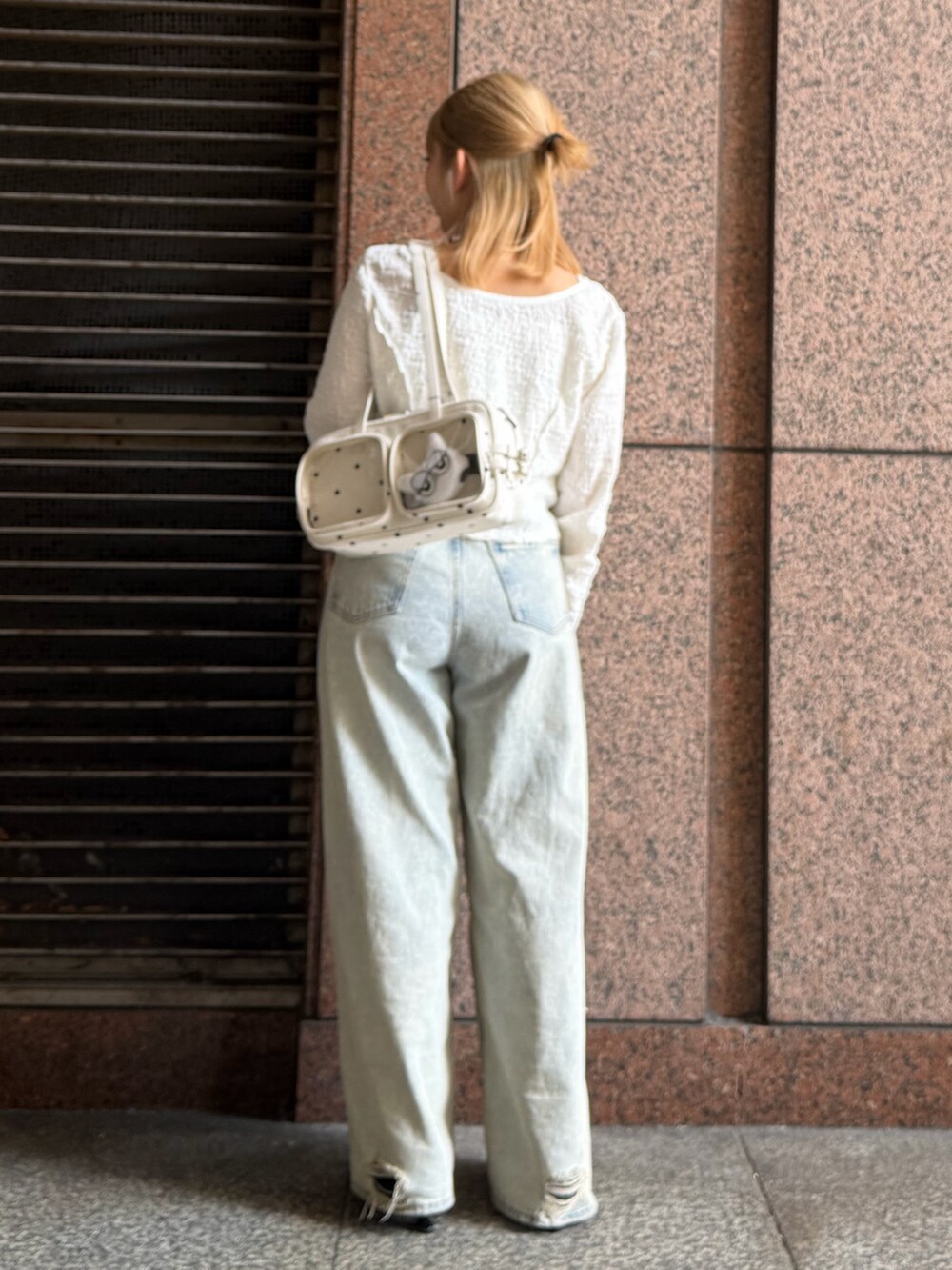 ホワイト系のTシャツ/カットソー、ブルー系のデニムパンツ、ホワイト系のショルダーバッグを着用したレディースの春コーディネートの3枚目の写真