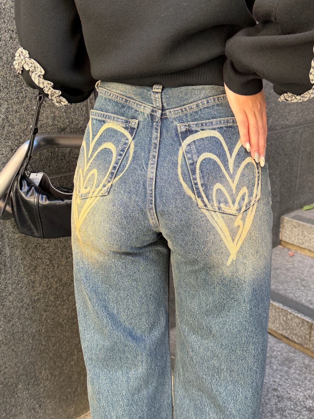 ブラック系のニット/セーター、ブルー系のデニムパンツ、ブラック系のショルダーバッグを着用したレディースの冬コーディネートの8枚目の写真