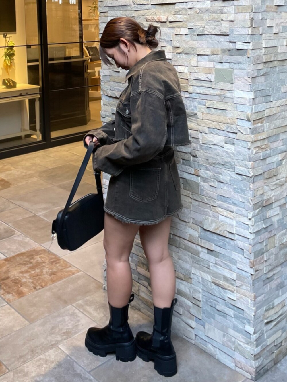 ブラック系のブーツ、ブラック系のハンドバッグ、ブラウン系のデニムジャケットを着用したレディースの秋コーディネートの2枚目の写真