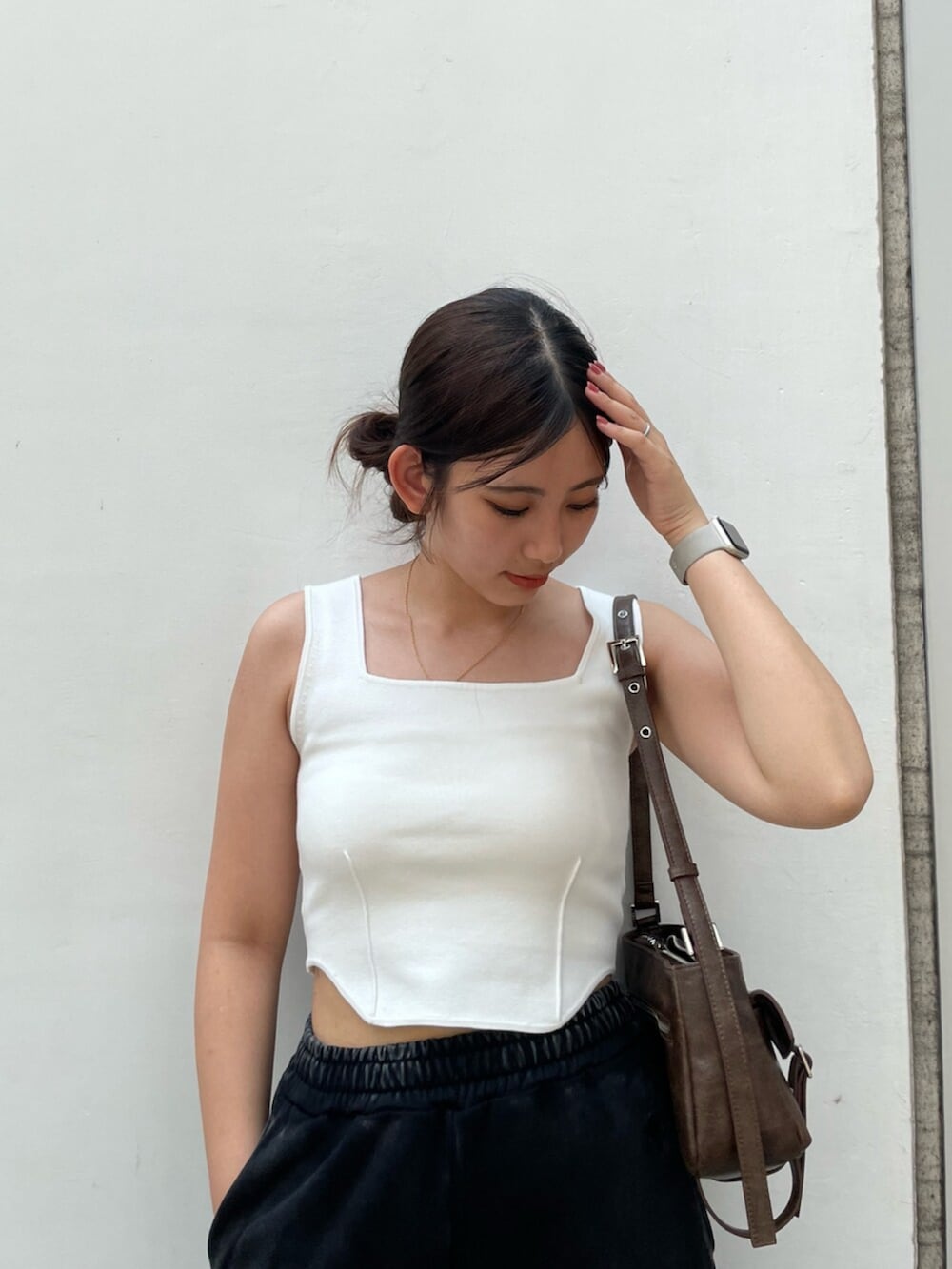 ブラック系のサンダル、ブラウン系のハンドバッグ、ホワイト系のニット/セーターを着用したレディースの夏コーディネートの4枚目の写真