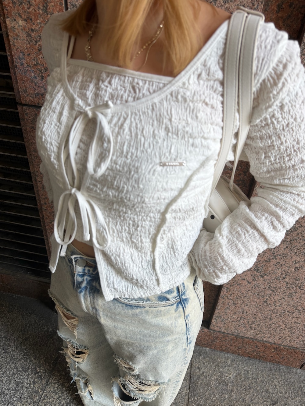 ホワイト系のTシャツ/カットソー、ブルー系のデニムパンツ、ホワイト系のショルダーバッグを着用したレディースの春コーディネートの6枚目の写真