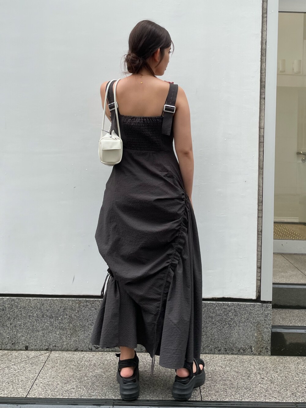グレー系のワンピース、ブラック系のサンダル、ホワイト系のハンドバッグを着用したレディースの夏コーディネートの3枚目の写真