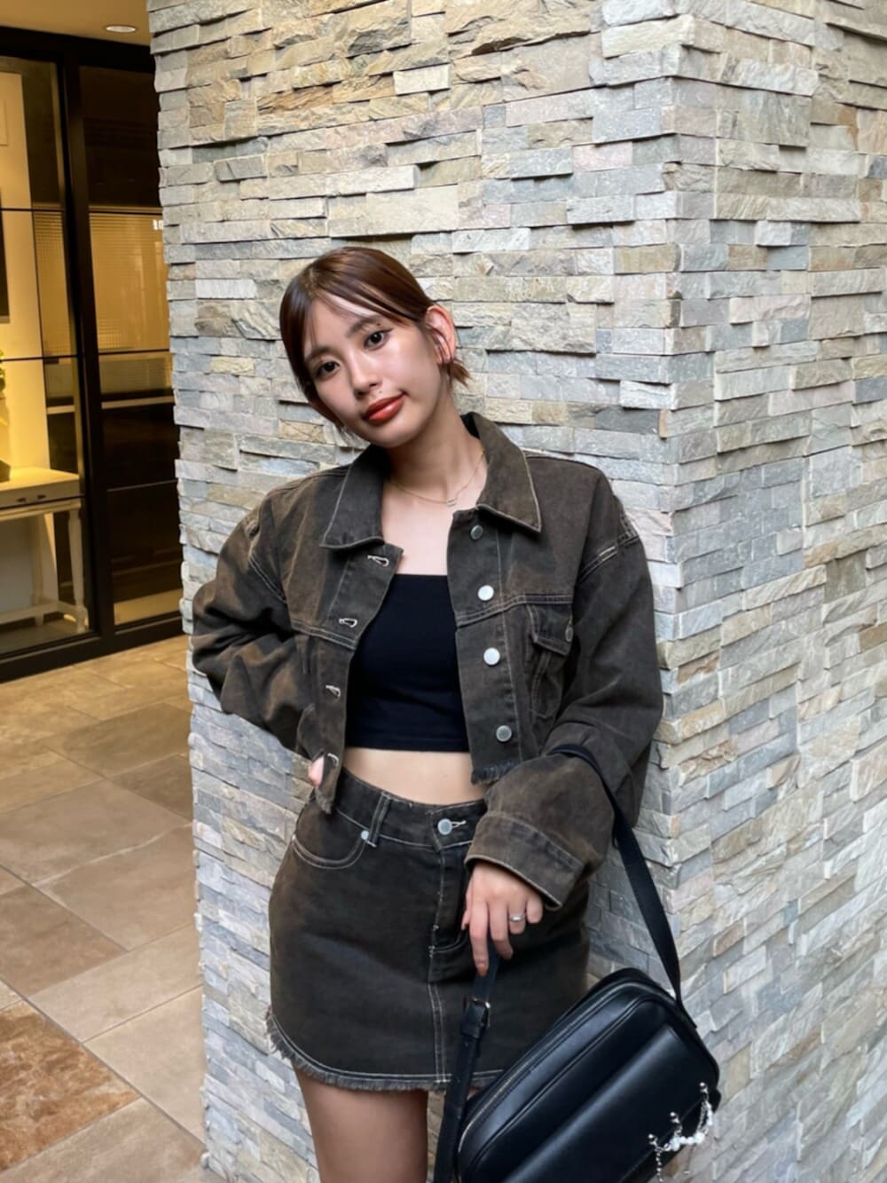 ブラック系のブーツ、ブラック系のハンドバッグ、ブラウン系のデニムジャケットを着用したレディースの秋コーディネートの4枚目の写真