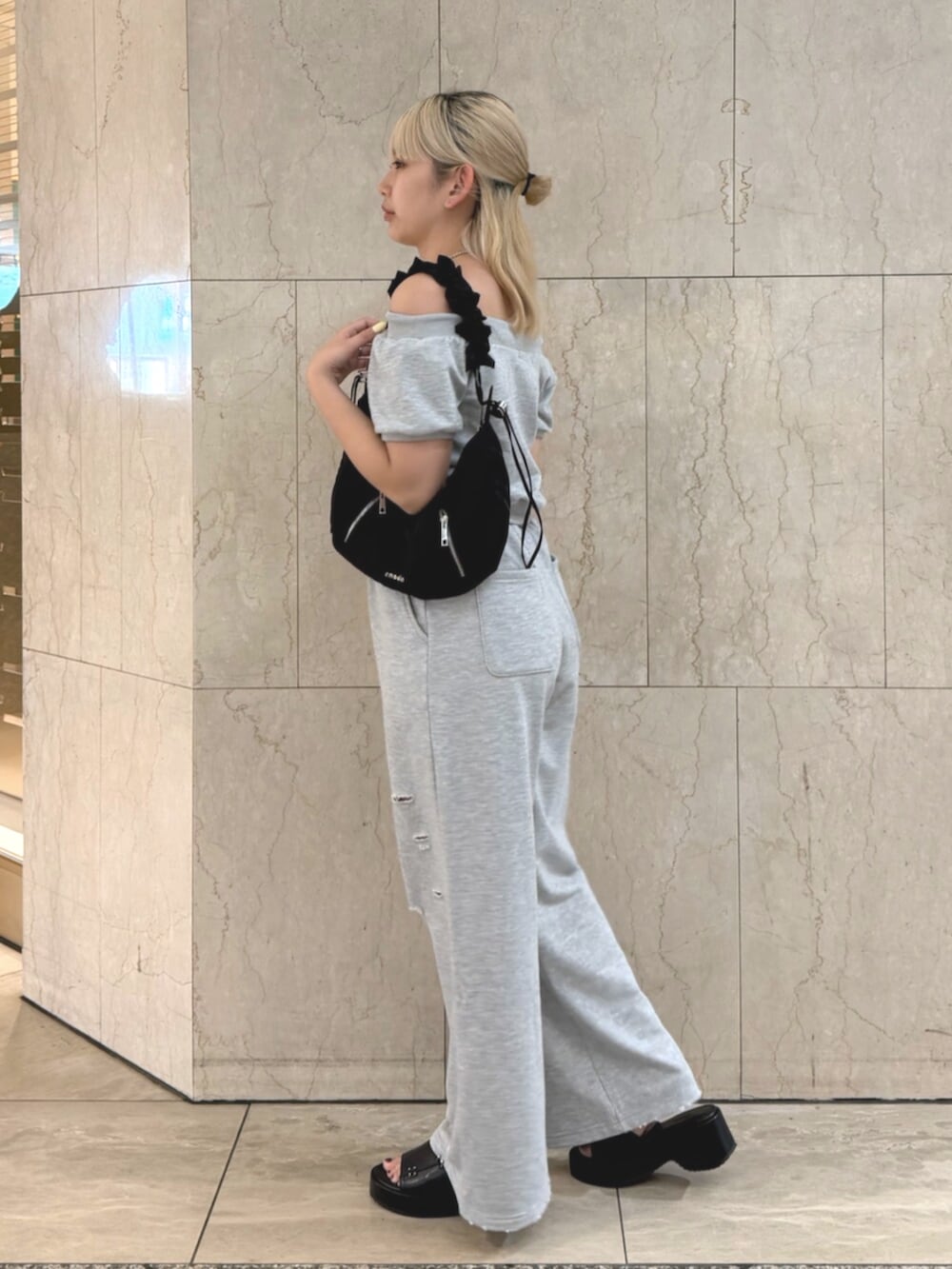 グレー系のスウェット、グレー系のスウェットパンツ、ブラック系のショルダーバッグを着用したレディースの夏コーディネートの2枚目の写真