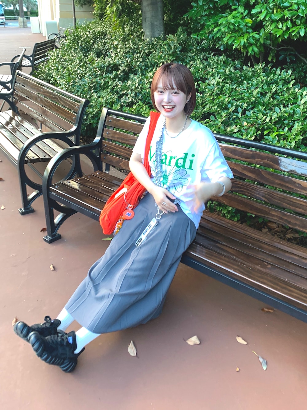 ホワイト系のTシャツ/カットソー、オレンジ系のトートバッグ、グレー系のスカートを着用したレディースの夏コーディネートの2枚目の写真