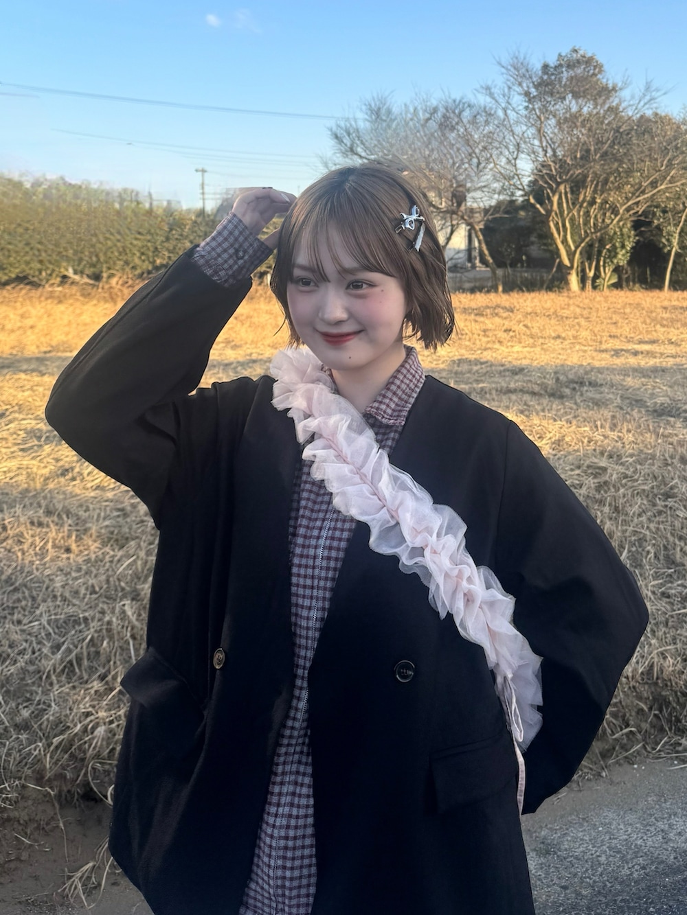 ブラック系のノーカラージャケット、ホワイト系のスカート、ブルー系のデニムパンツを着用したレディースの冬コーディネートの2枚目の写真