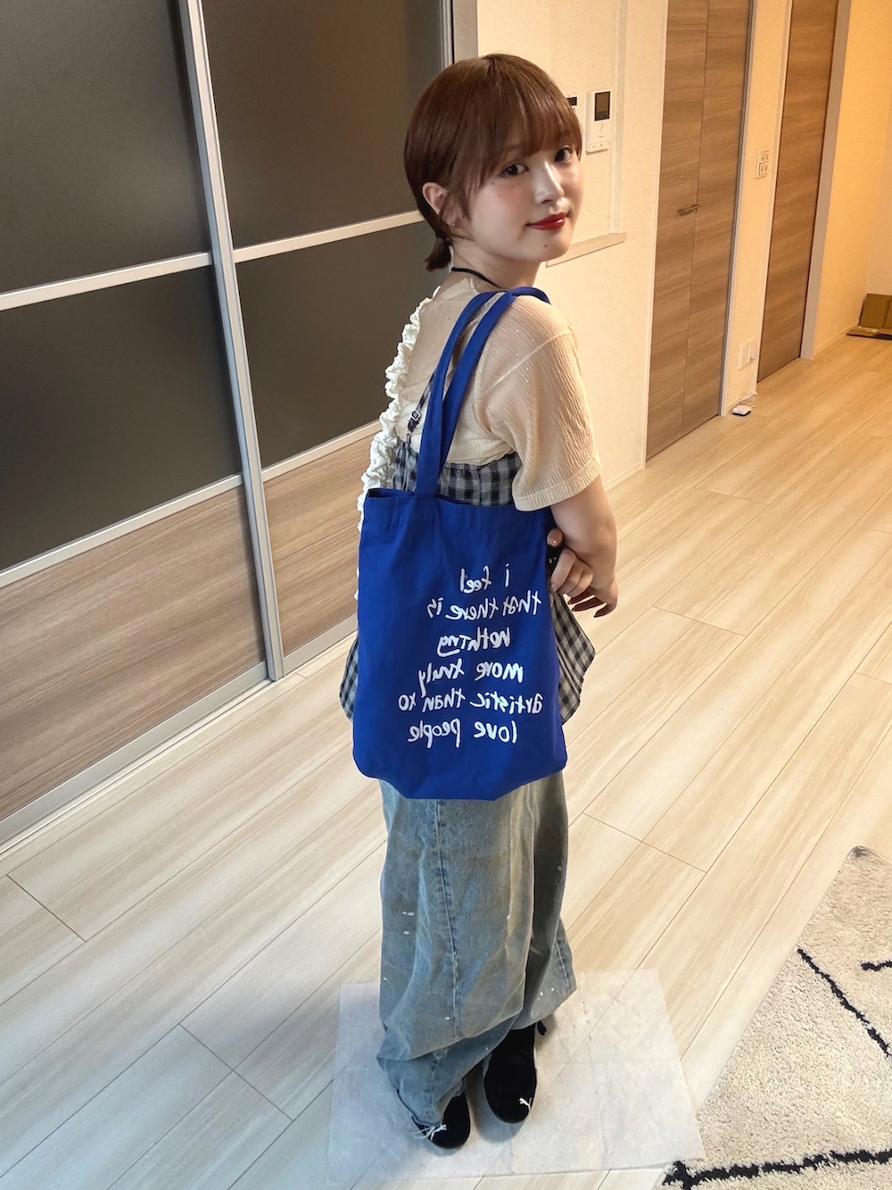 ブルー系のデニムパンツ、ブラック系のスニーカー、ベージュ系のTシャツ/カットソーを着用したレディースの夏コーディネートの2枚目の写真