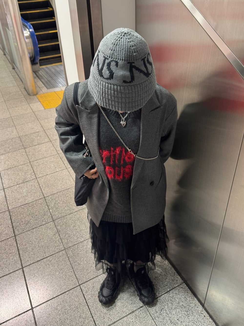 グレー系のテーラードジャケット、グレー系のニット/セーター、ブラック系のスニーカーを着用したレディースの冬コーディネートの2枚目の写真