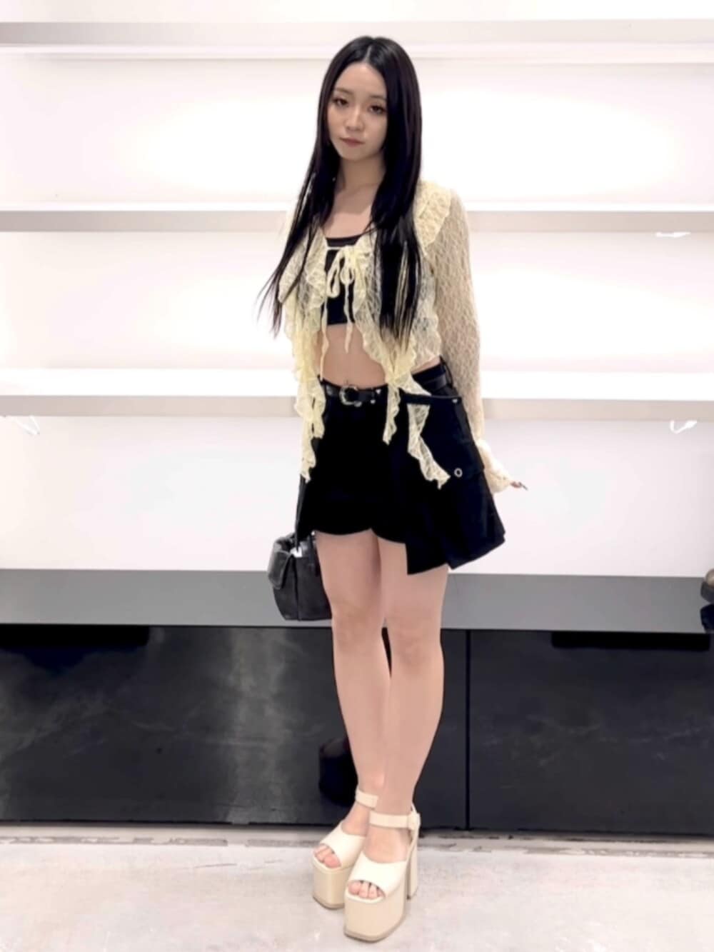 ブラック系のハンドバッグ、ブラック系のスカート、イエロー系のTシャツ/カットソーを着用したレディースの春コーディネートの2枚目の写真