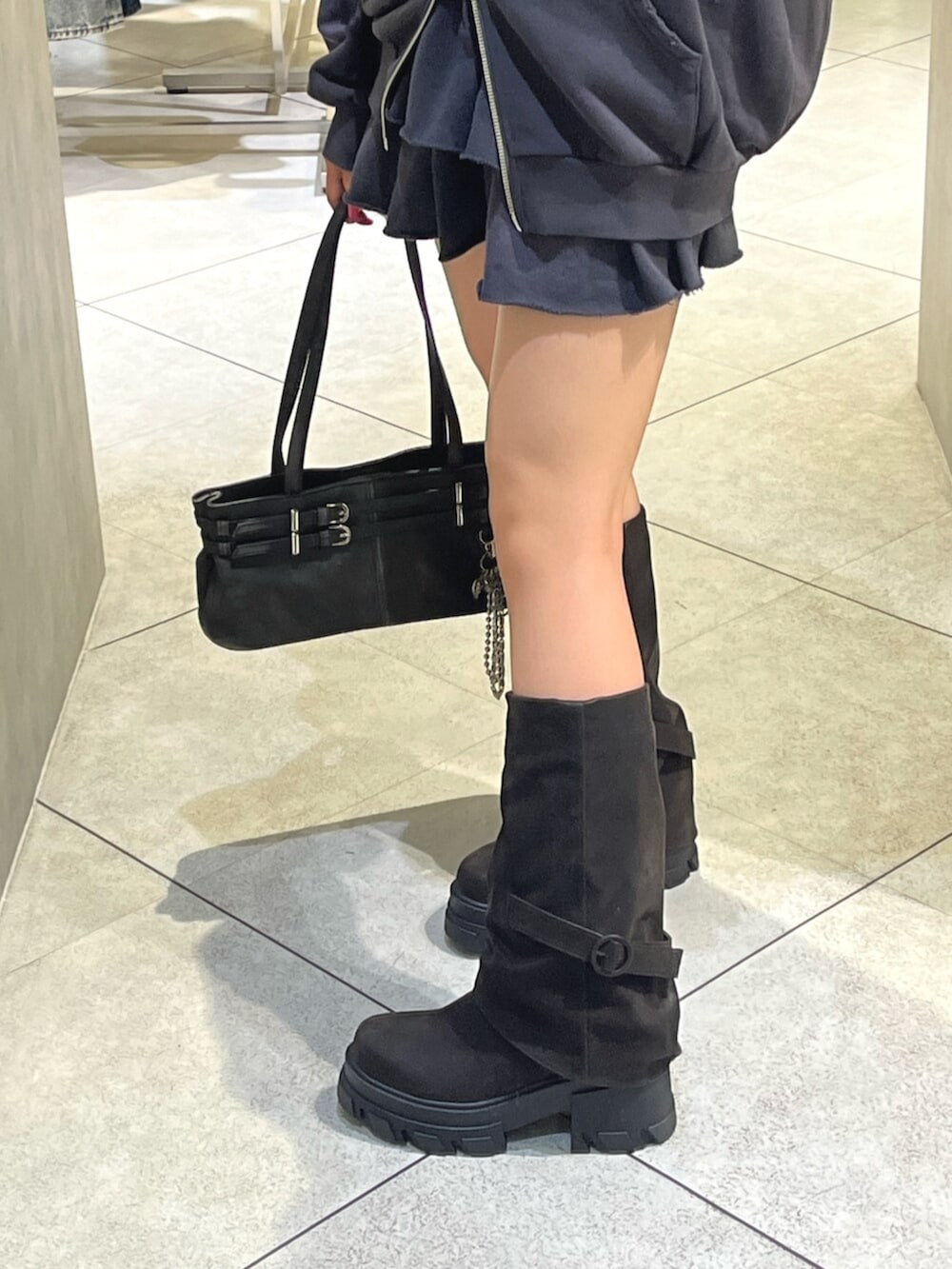 グレー系のパーカー、グレー系のスカート、ブラック系のショルダーバッグを着用したレディースの秋コーディネートの9枚目の写真
