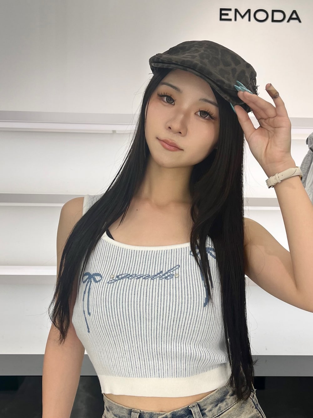 ブルー系のデニムパンツ、ブラック系のサンダル、ブラウン系のハンチング/ベレー帽を着用したレディースの夏コーディネートの5枚目の写真