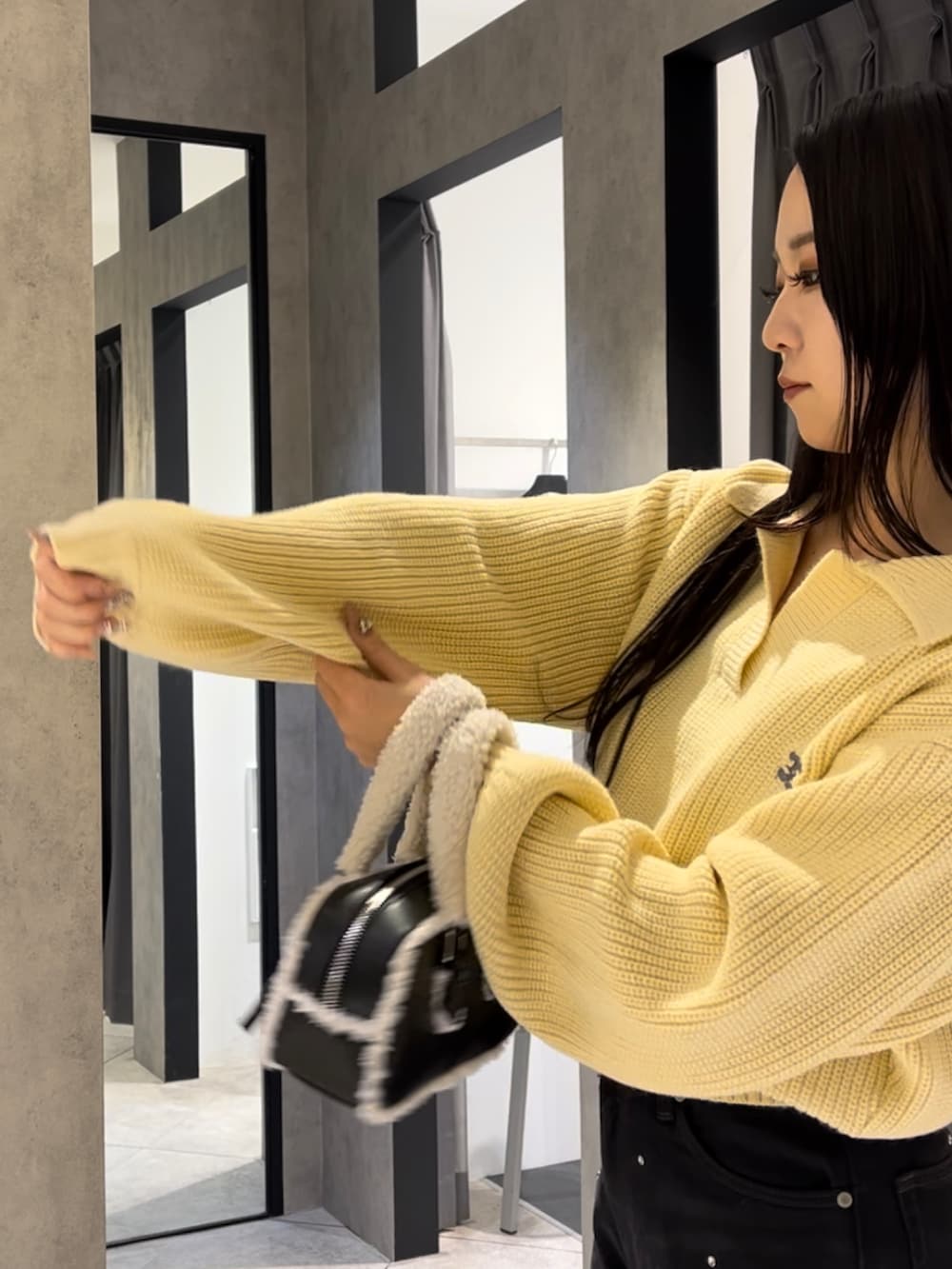 イエロー系のニット/セーター、ブラック系のデニムパンツ、ブラック系のハンドバッグを着用したレディースの冬コーディネートの8枚目の写真