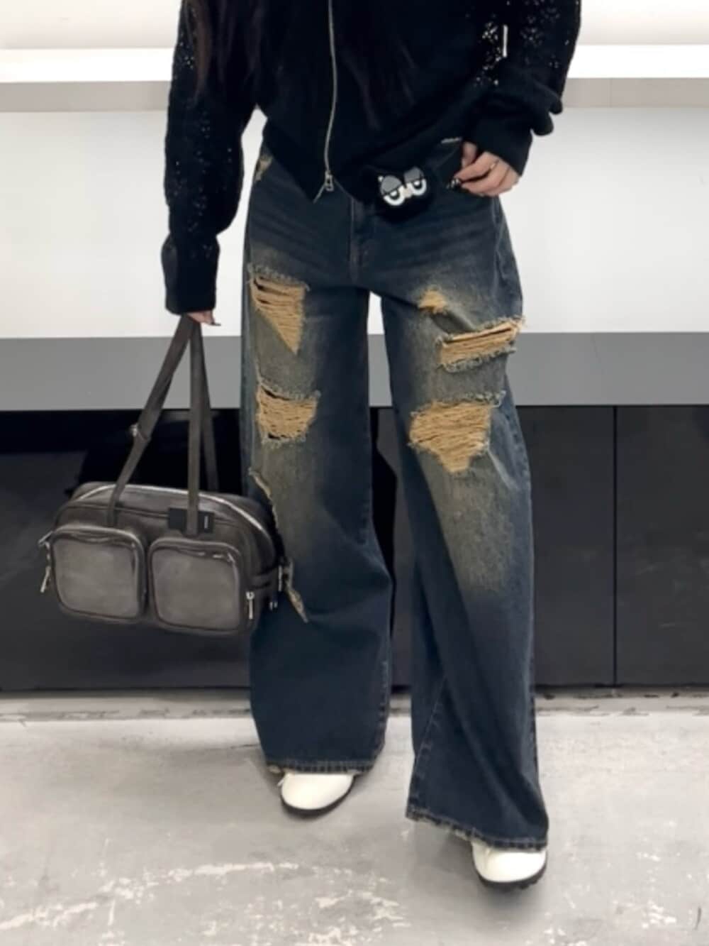 ホワイト系のスニーカー、ブルー系のデニムパンツ、ブラック系のパーカーを着用したレディースの春コーディネートの6枚目の写真