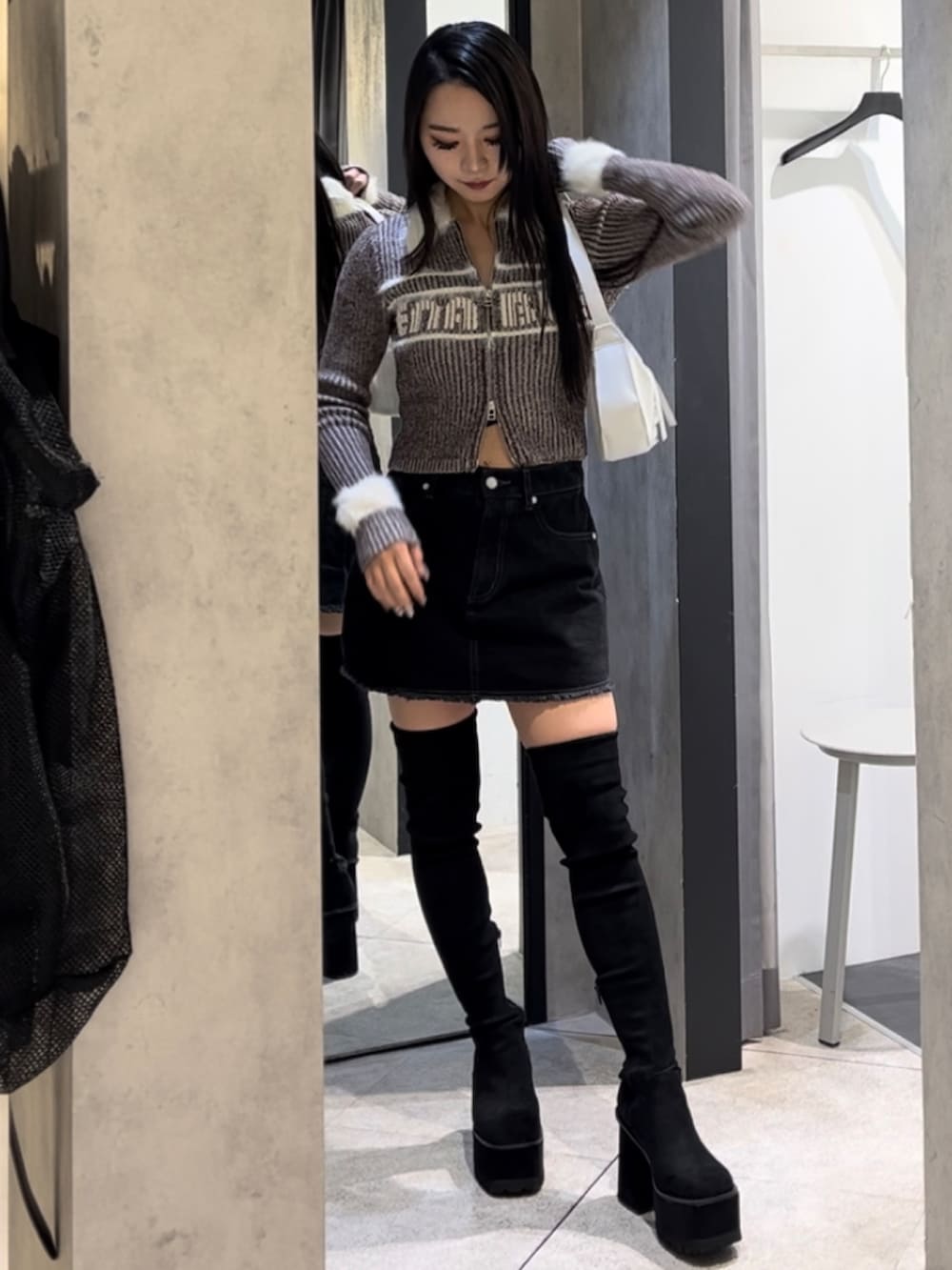 ブラウン系のニット/セーター、ブラック系のスカート、ホワイト系のショルダーバッグを着用したレディースの冬コーディネートの8枚目の写真