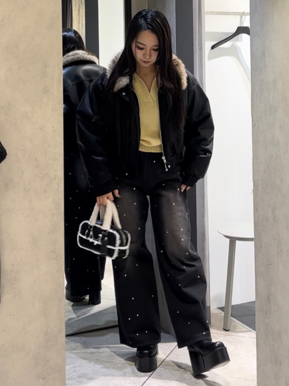 イエロー系のニット/セーター、ブラック系のデニムパンツ、ブラック系のハンドバッグを着用したレディースの冬コーディネートの4枚目の写真