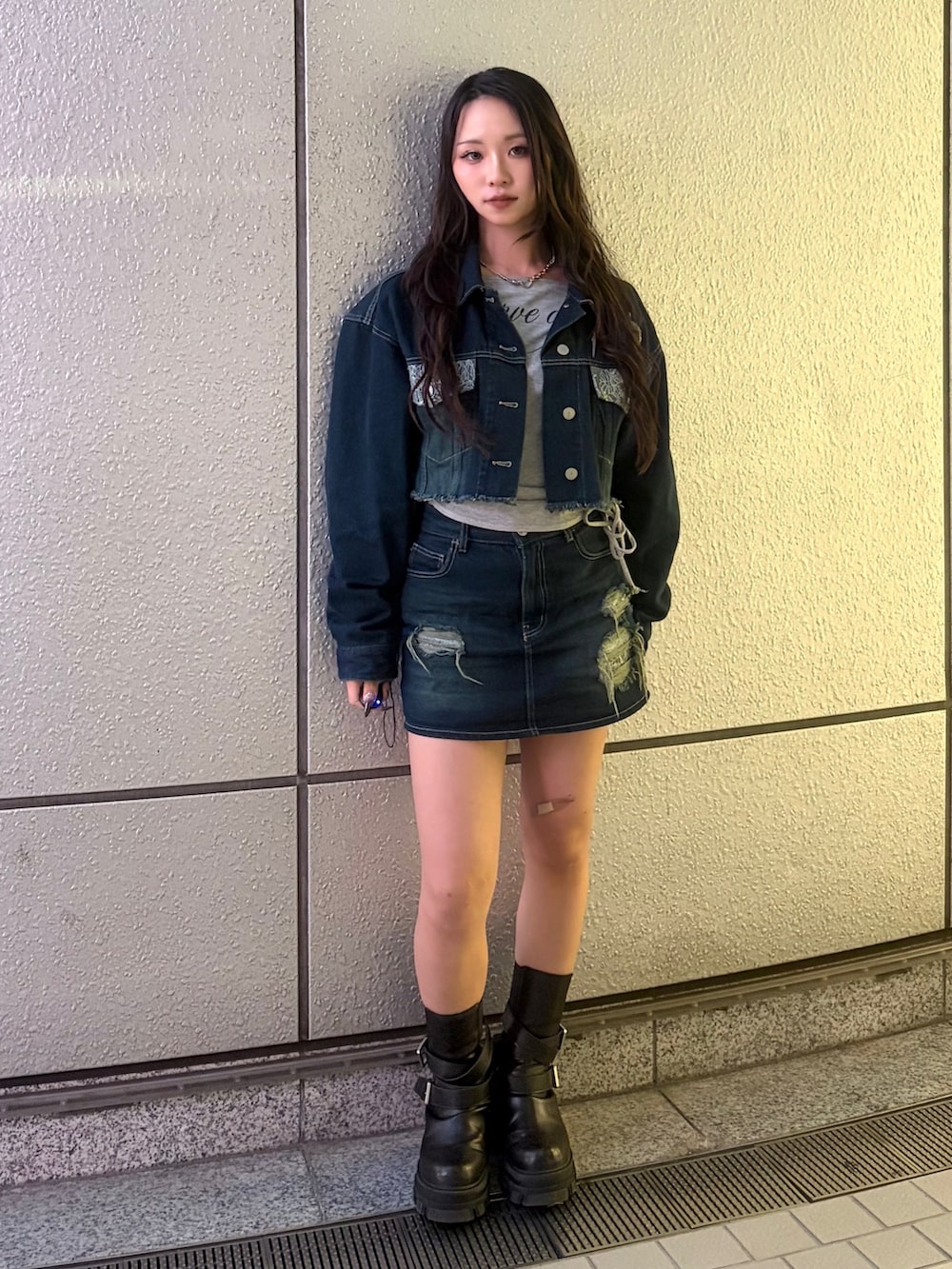 ブルー系のスカート、ブラック系のブーツ、グレー系のTシャツ/カットソーを着用したレディースの秋コーディネートの2枚目の写真