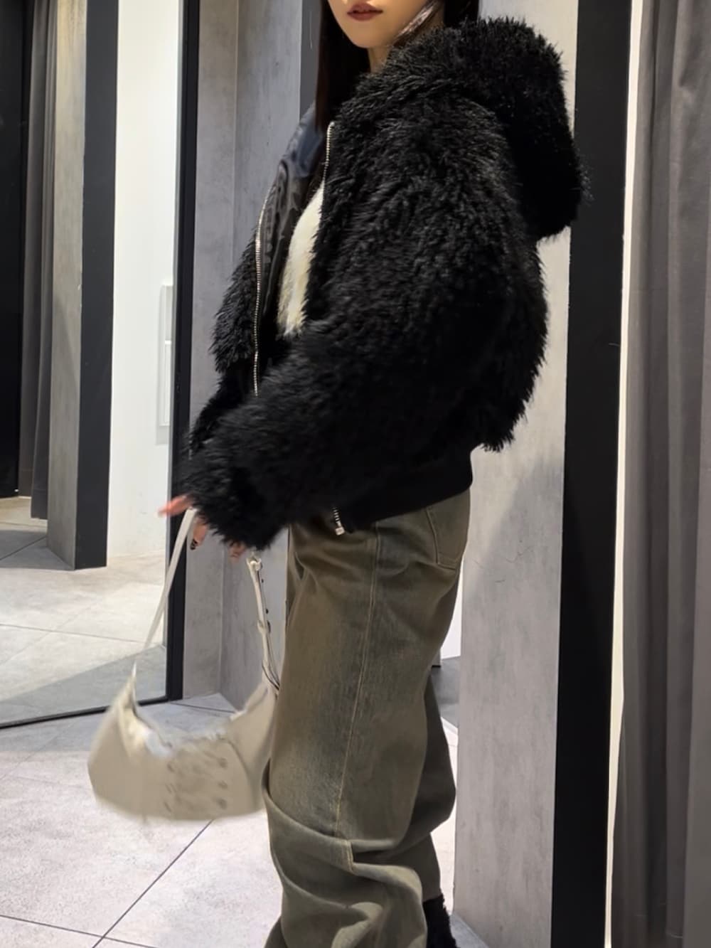 ブラック系のブルゾン、ホワイト系のニット/セーター、ブルー系のデニムパンツを着用したレディースの冬コーディネートの6枚目の写真