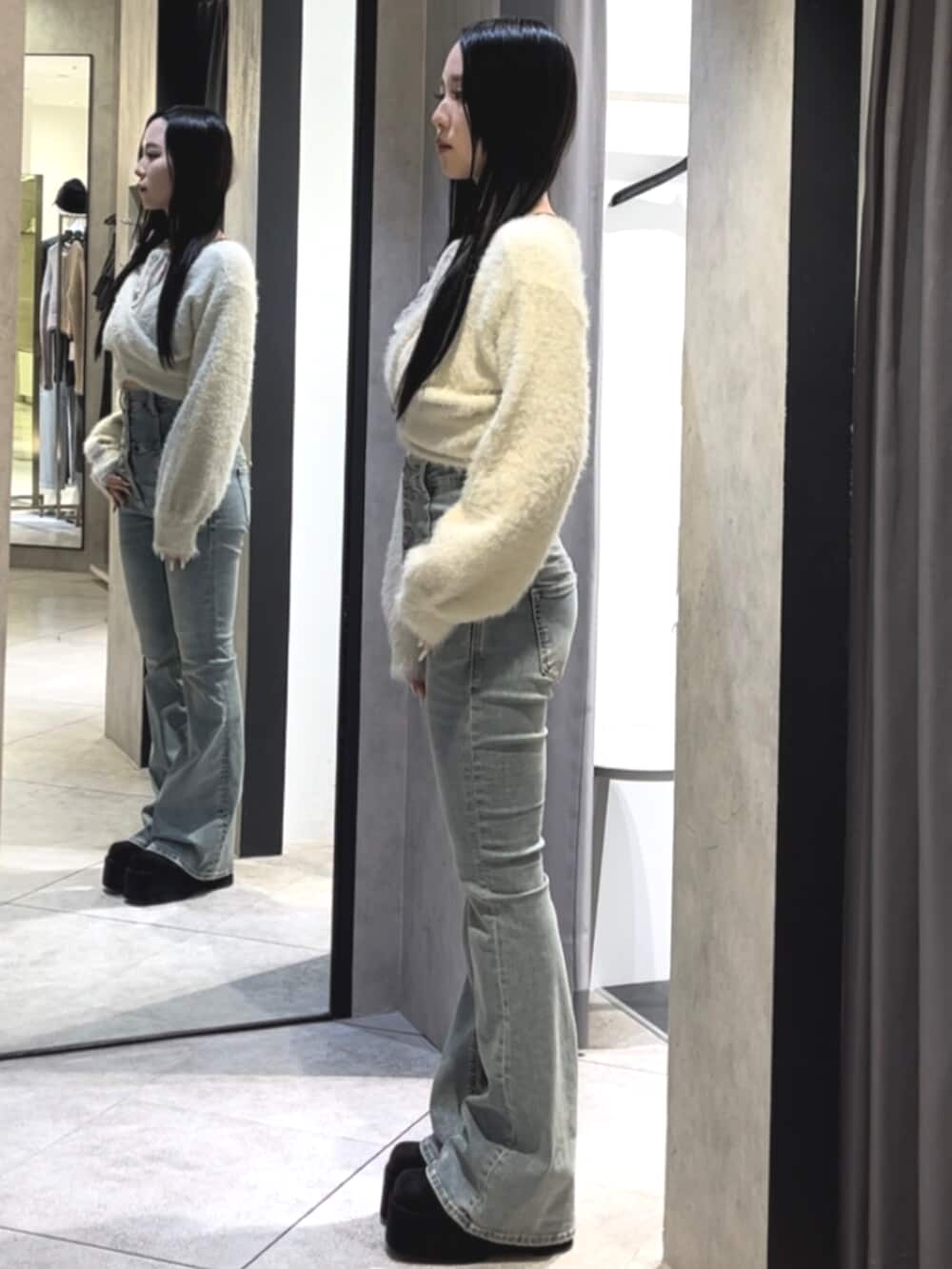 ブルー系のデニムパンツ、ホワイト系のニット/セーター、ブラック系のブーツを着用したレディースの冬コーディネートの2枚目の写真